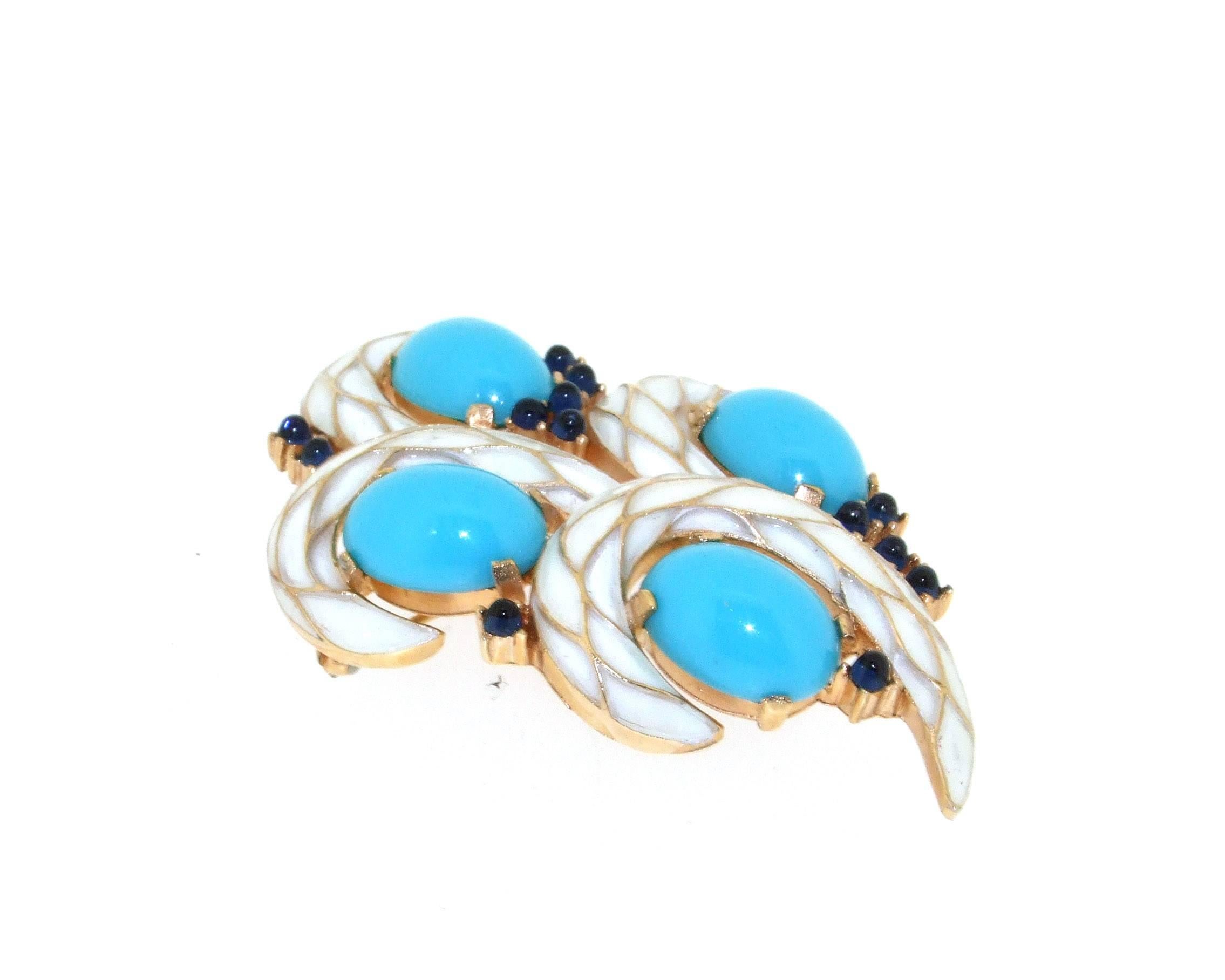 A stylish vintage brooch by Trifari, set in gold tone costume metal and decorated with white enamel, turquoise and sapphire blue glass stones. 

This piece was made as part of the L'Orient collection in 1968.

It measures 6.3cm high by 4.1cm