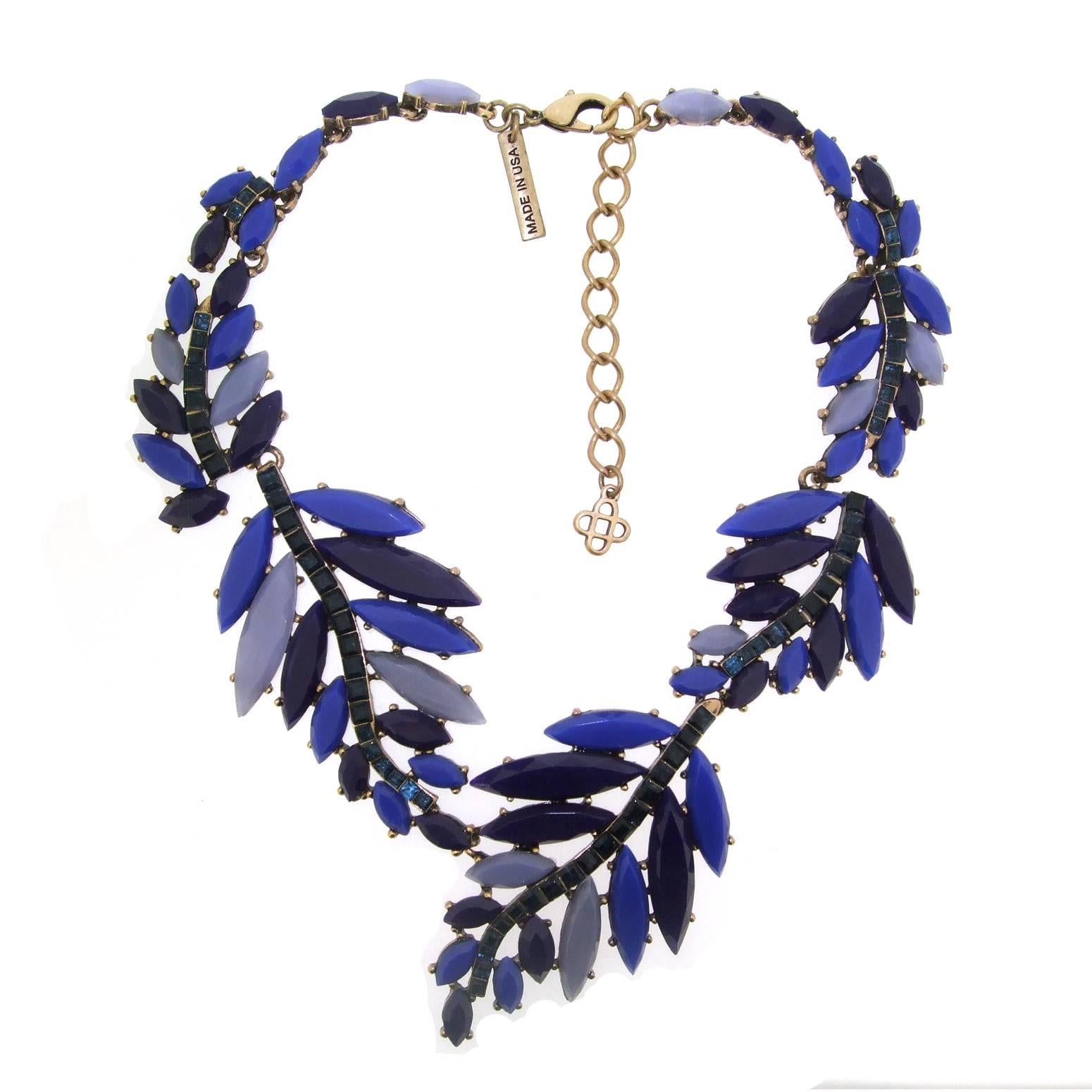 A stunning statement necklace by Oscar De La Renta set with 4 toned blue acrylic and crystal stones in gold tone costume metal. The 'leaves' are acrylic blues and running along the centre are square royal blue swarovski crystals. 

The length is 16-