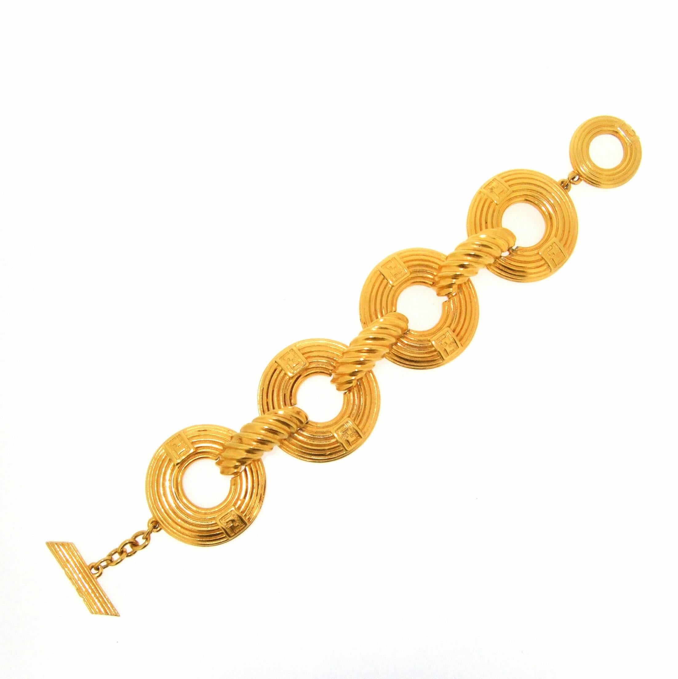 A Vintage Bracelet by Fendi in gold plated metal. Gold hoops joined together with a toggle fastening into a hoop. Each component part is stamped FENDI either once or twice per piece and each hoop is stamped with the FF logo twice on the front.
