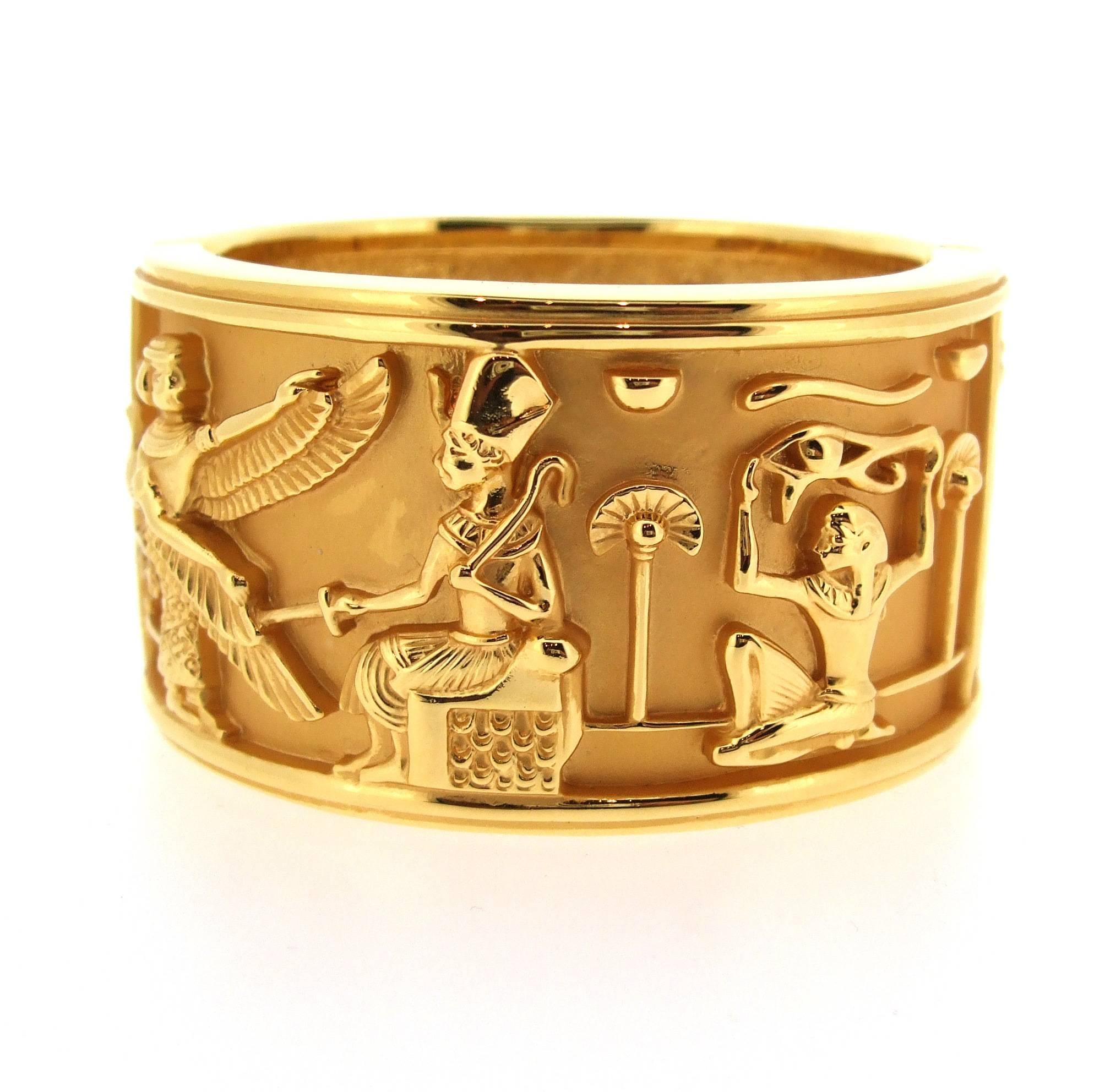 A piece of the 1994 Elizabeth Taylor for Avon collection featuring Egyptian characters in daily life, in a montage in various different poses all the way around.  A gold plated clamper bracelet that opens up to fit around the wrist. 

Elizabeth