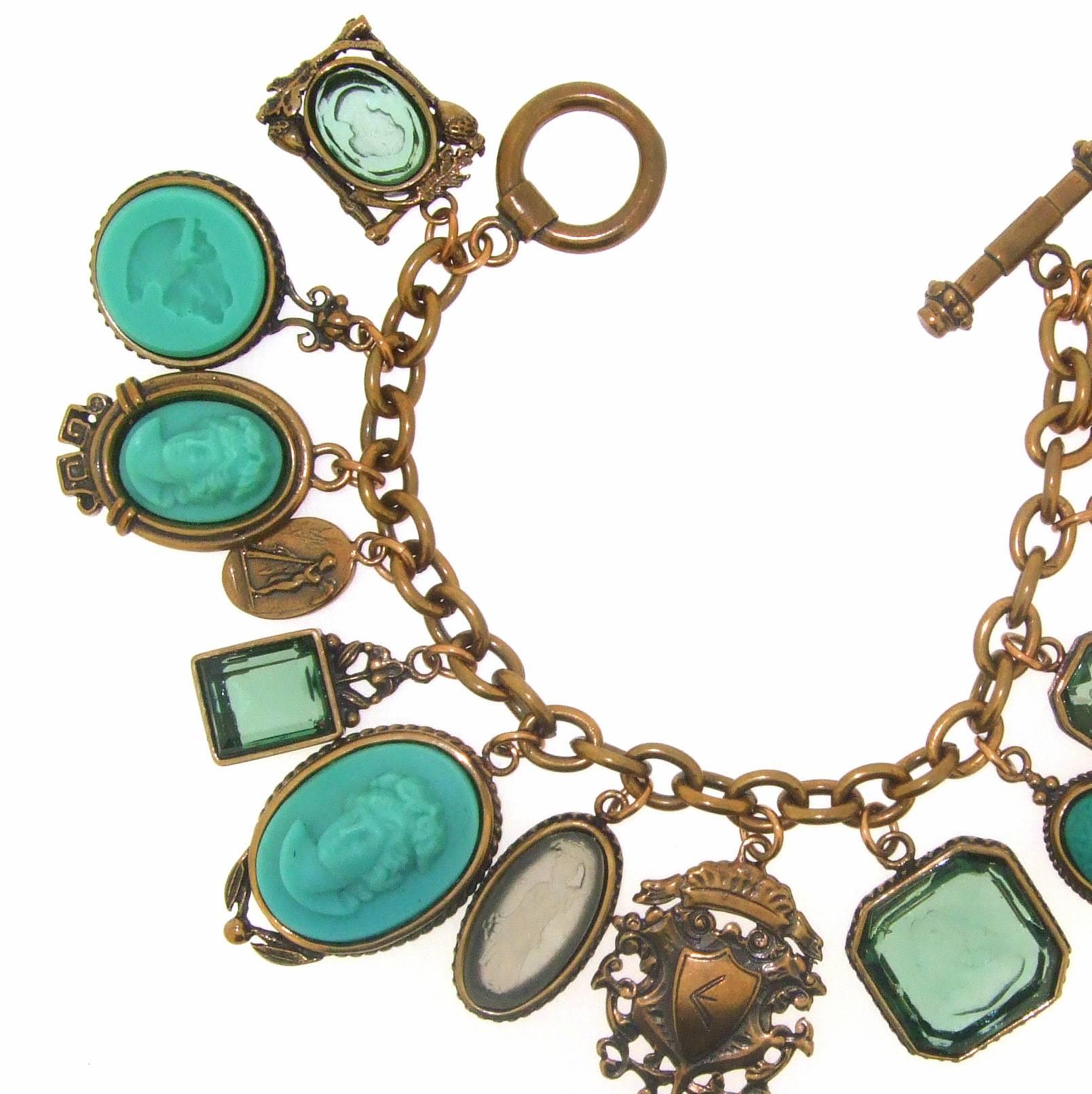 A charm bracelet by Extasia USA featuring hand pressed German glass cameos and intaglios set in bronze chain and metal casings. 

The largest charm measures 3.5cm by 2.1cm. 