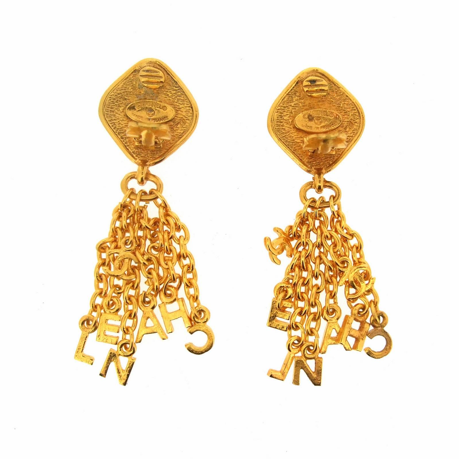 A fabulous pair of statement clip on earrings by Chanel featuring charms tassell letters spelling CHANEL with and extra cc logo charm. 

The Chanel cartouche dates to the 1980s.