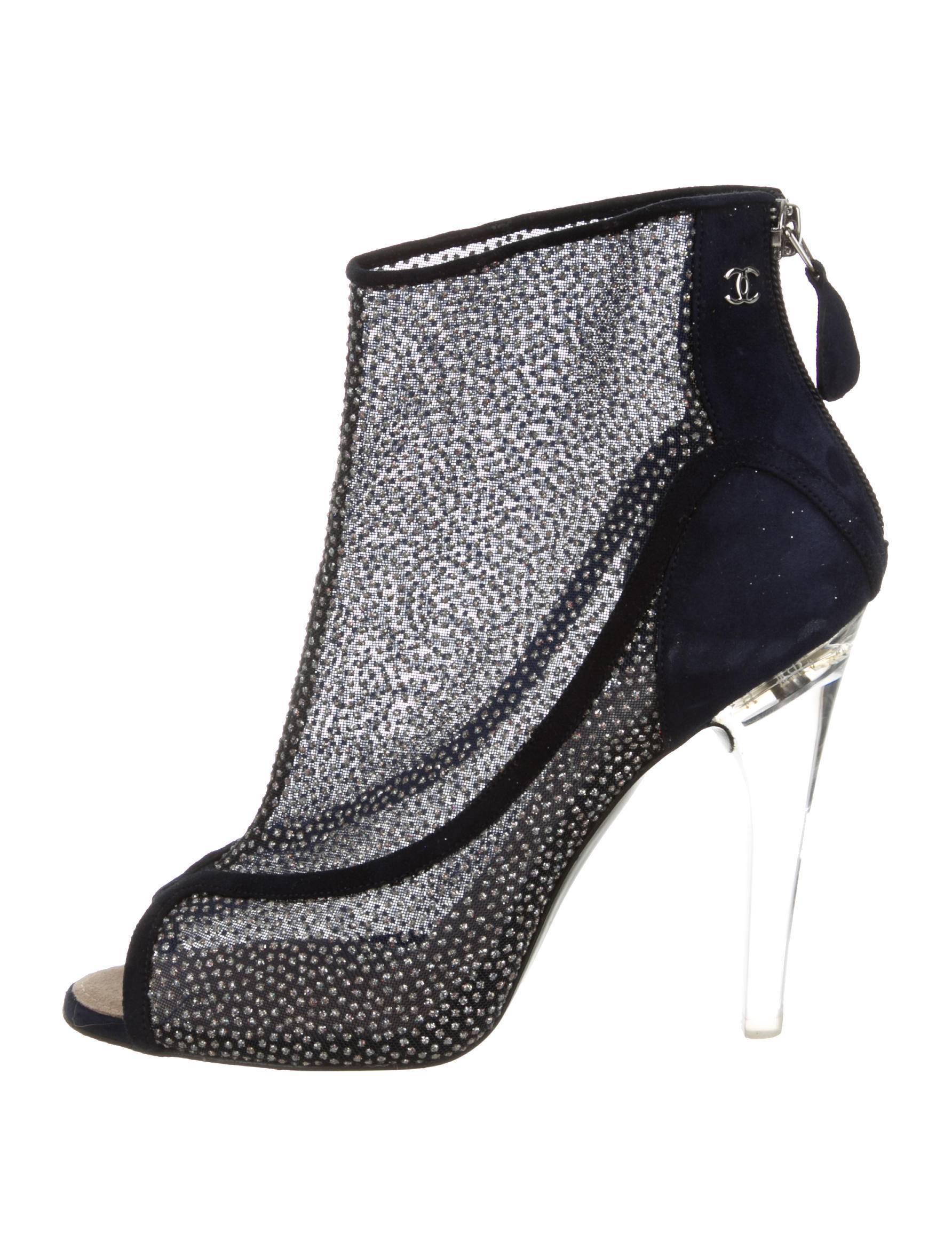 CURATOR'S NOTES

Ultra fab Chanel peep-toe booties with suede trim, silver-tone glitter embellishments throughout, interlocking CC embellishment at side, lucite heels and zip closure at counter. 

Size IT 37.5 (US7.5)
Mesh
Suede
Lucite