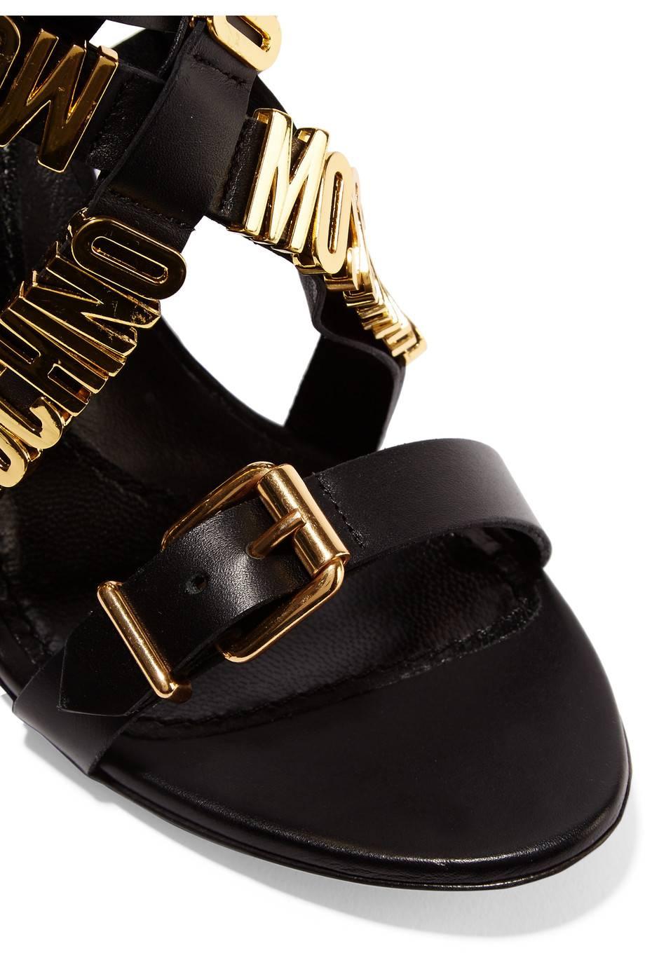 CURATOR'S NOTES

Let your feet do the talking with these brand NEW and SOLD OUT Moschino black leather sandals featuring gold plated 