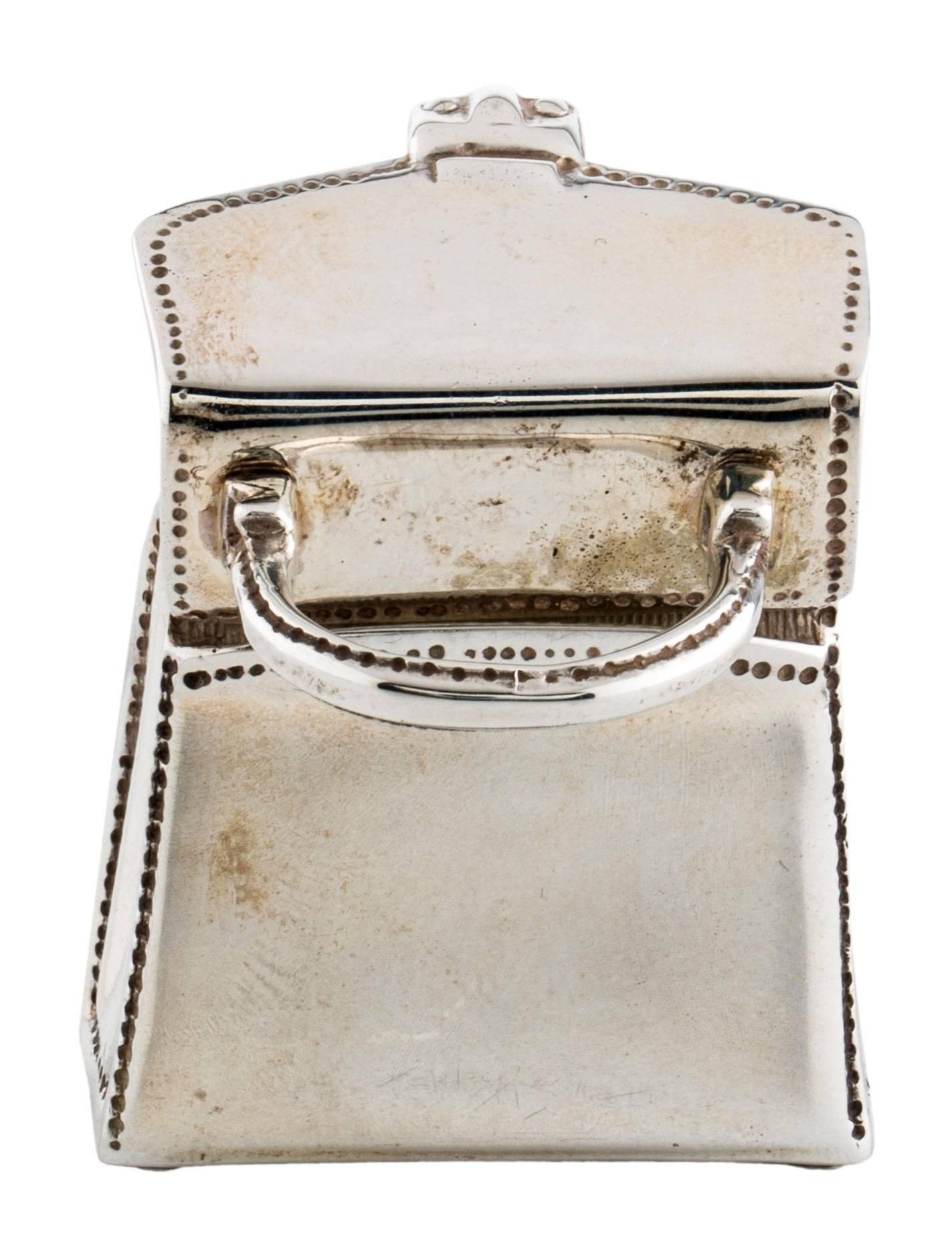 CURATOR'S NOTES

Tiffany & Co Genuine Sterling Silver Hand Bag Pendant Pill Trinket Box Accessory

Sterling silver - 925
Hinge closure
Signed
Measures 1.25" W x 1.75" H x 0.50" D 
Includes original Tiffany & Co dust bag
