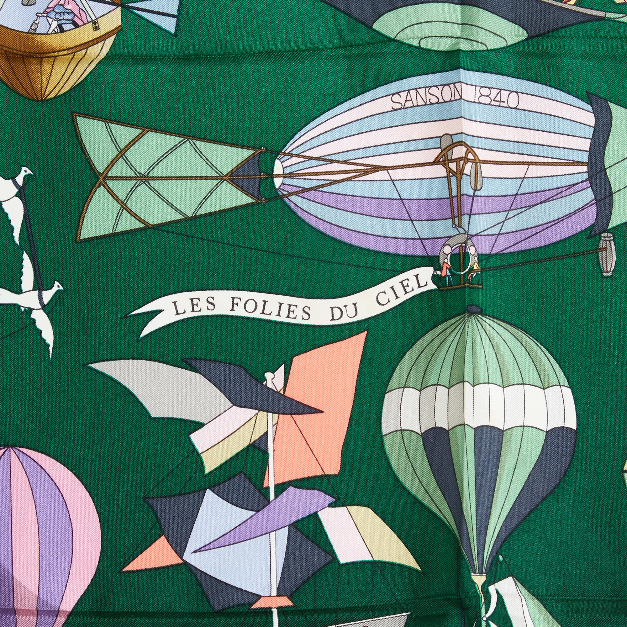 Foulard quadrato 90 di Hermès in twill di seta, motivo Les Folies du Ciel di Loïc Dubigeon, pubblicato nel 1984 e riedito nel 1990 (come questo), con sfumature di verde che vanno dal chiaro allo scuro, bordo verde a gradiente inverso. Larghezza 90