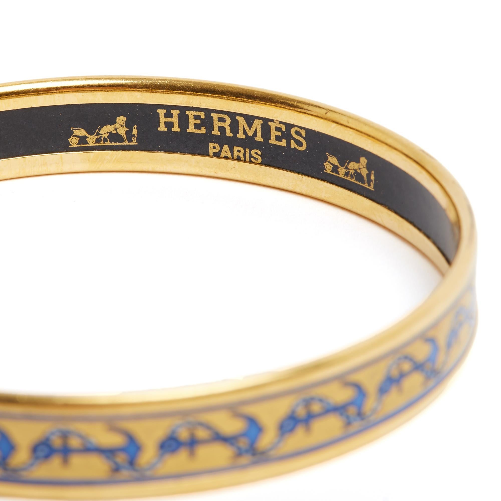 Pulsera Hermès modelo Thin de esmalte estampado, motivo Chaine d'Ancre en tonos azules sobre fondo dorado, metal dorado. Talla 65 o Internacional S: diámetro interior 6,3 cm, longitud total aproximada 20,3 cm, altura 0,9 cm. La pulsera es vintage
