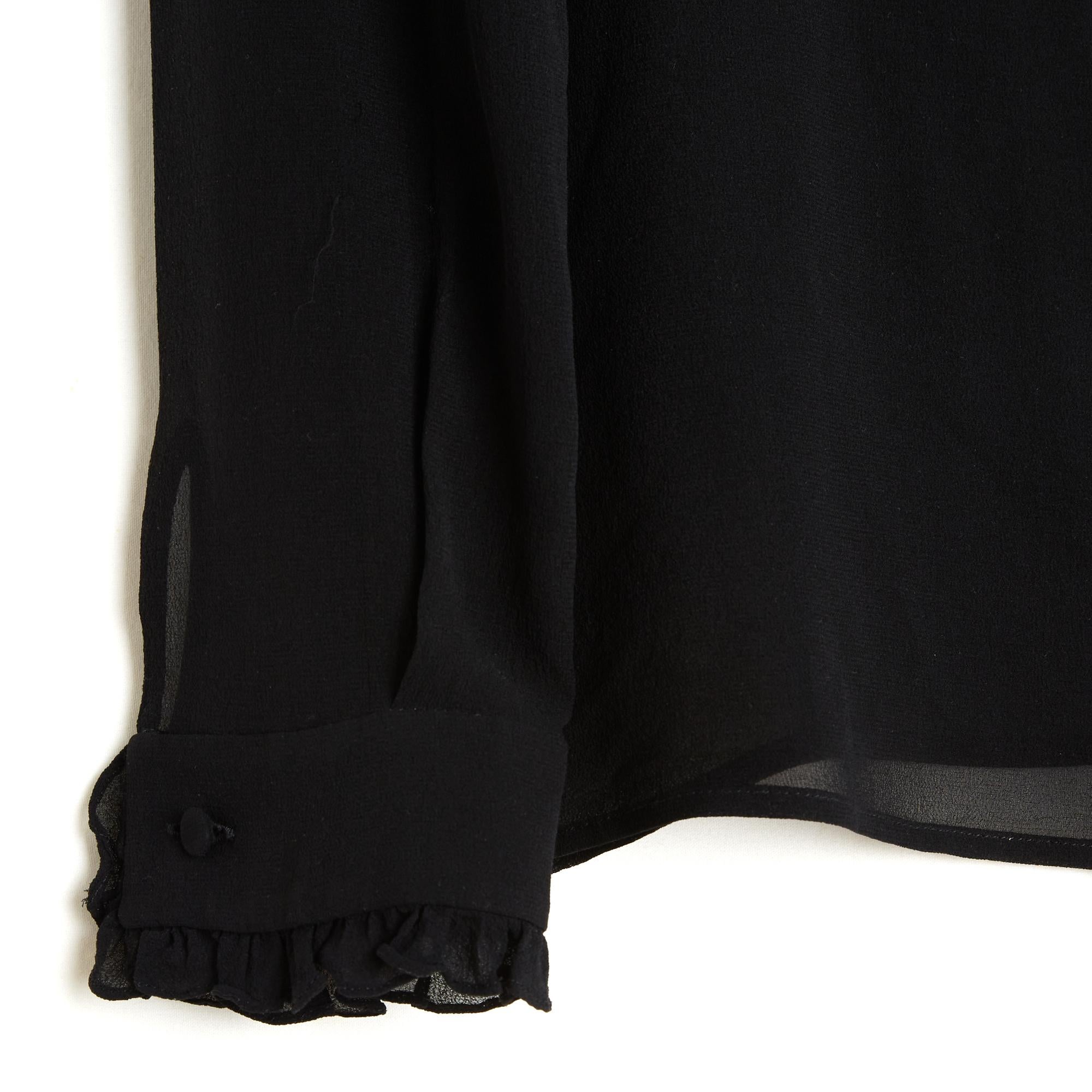 Top Saint Laurent 2014 by Hedi Slimane in crêpe di seta nera semitrasparente, colletto a camicia decorato con un piccolo volant, chiuso da 8 bottoni, maniche lunghe chiuse da un doppio bottone e bordate con lo stesso volant. Taglia FR36 o UK8 e US4