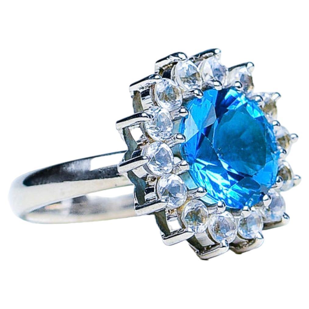 The Natural 5ct Round Natural Blue Topaz Cocktail Ring. This exquisite piece marries the purity of simplicity of white Zircons with the brilliance of a genuine blue topaz, resulting in a timeless and sophisticated accessory.

Product