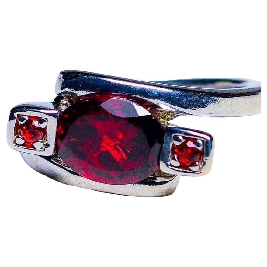 Wir präsentieren unseren 2ct Oval Rhodolite Red Garnet Platinum Silver 3-Stein-Ring, ein atemberaubendes Stück, das Eleganz und Raffinesse ausstrahlt. In der Mitte dieses Rings befindet sich ein ovaler roter Rhodolith-Granat von 2 Karat, der für