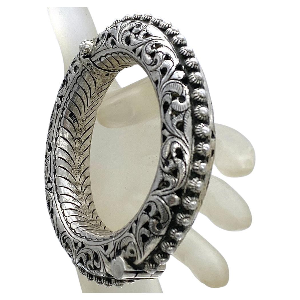 Si tratta di un braccialetto in argento sterling realizzato a mano in stile etnico dell'Asia meridionale. Questo braccialetto pesante 103 grammi con un motivo dettagliato di foglie traforate è incernierato e ha una chiusura a strappo. Ha una