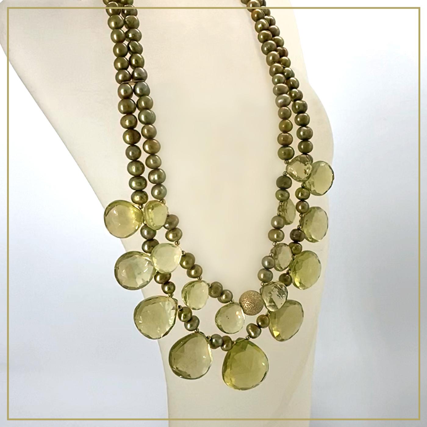 Ce collier à double brin a été créé avec des perles briolettes à cœur facetté en quartz citron de 20 mm de diamètre et des perles de culture d'eau douce de couleur or verdâtre. Une perle de focalisation en poussière d'étoiles de 10 mm de diamètre,