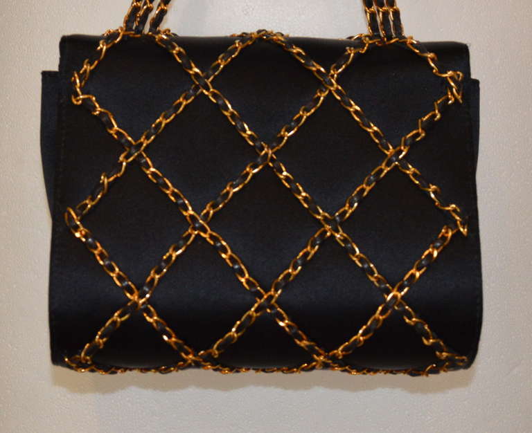 Chanel charming black satin night bag, quilted pattern in gold tone metal chains interlaced with black leather, magnetic closure. Long handle strap with three rows of black leather interlaced with gold tone metal. Golden leather inside, one pocket.