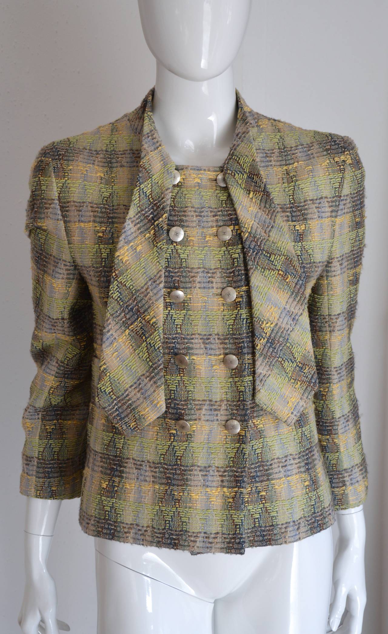 The very chic of Chanel in this cool tie-up jacket. Classy and modern with the graphic use of tweed, in the the tones kaki and beige.
CC patinated silver buttons, front and cuffs. Fully silk lining.