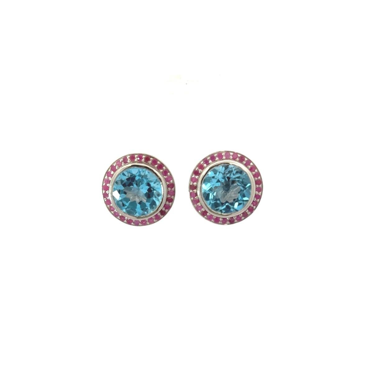 Questi audaci orecchini a cerchio in Topazio Blu e Rubino sono orecchini a cerchio vibranti, realizzati a mano in pregiato argento sterling 925. Al centro di ogni orecchino si trova un topazio blu brillante a taglio rotondo, incastonato in un