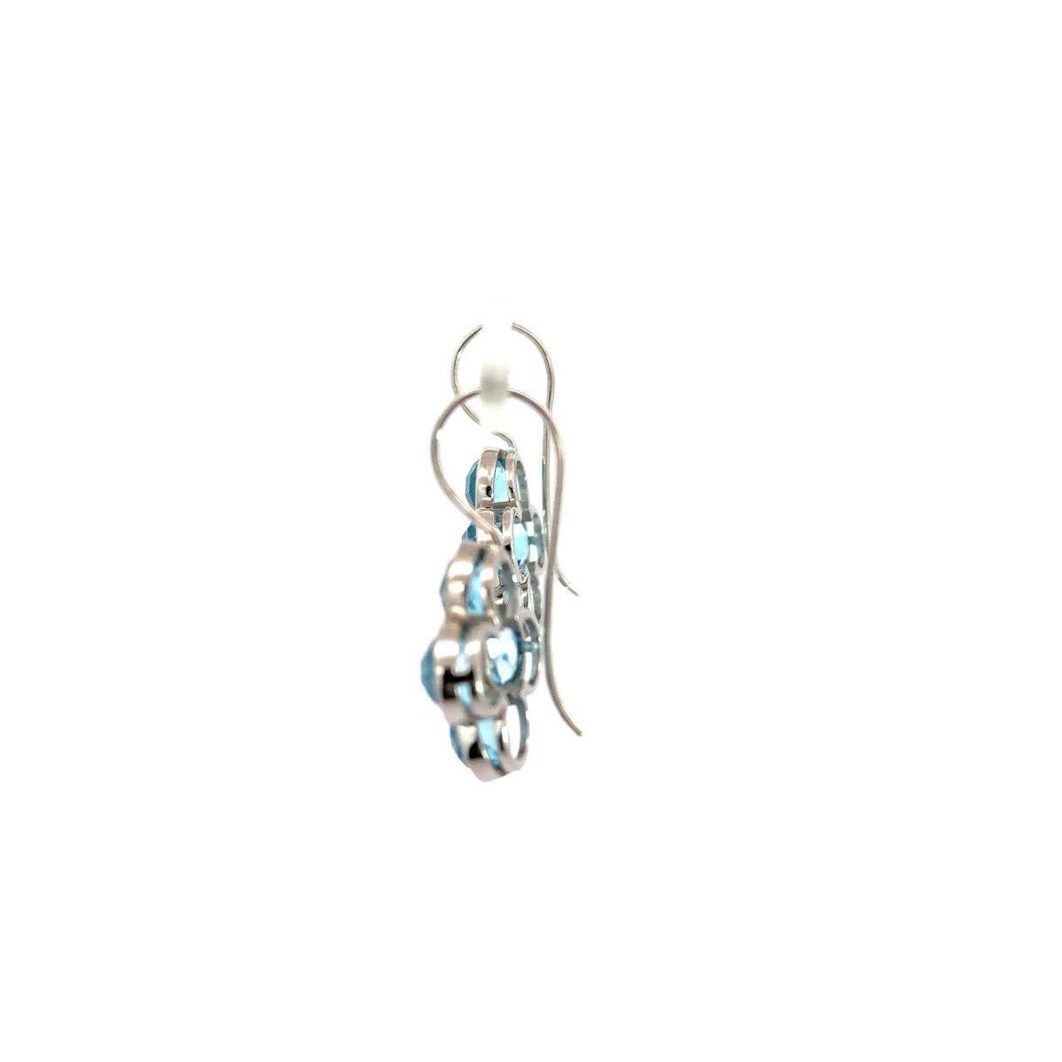 Questi orecchini pendenti contemporanei in argento con fiori di topazio blu naturale, realizzati a mano, sono caratterizzati da un radioso gruppo di pietre di topazio blu di taglio rotondo, incastonate nell'argento 925. Le vibranti gemme celesti