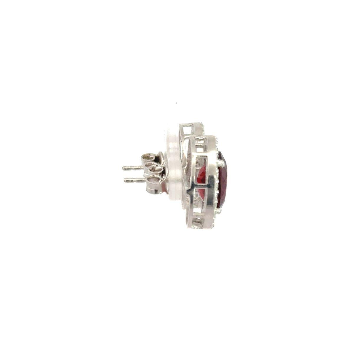 Questi orecchini a perno di ispirazione vintage con granato rosso e zircone a raggiera sono realizzati in argento 925. Ogni orecchino presenta una gemma rossa dal taglio profondo e ovale, che evoca un granato o un rubino, sapientemente incastonata