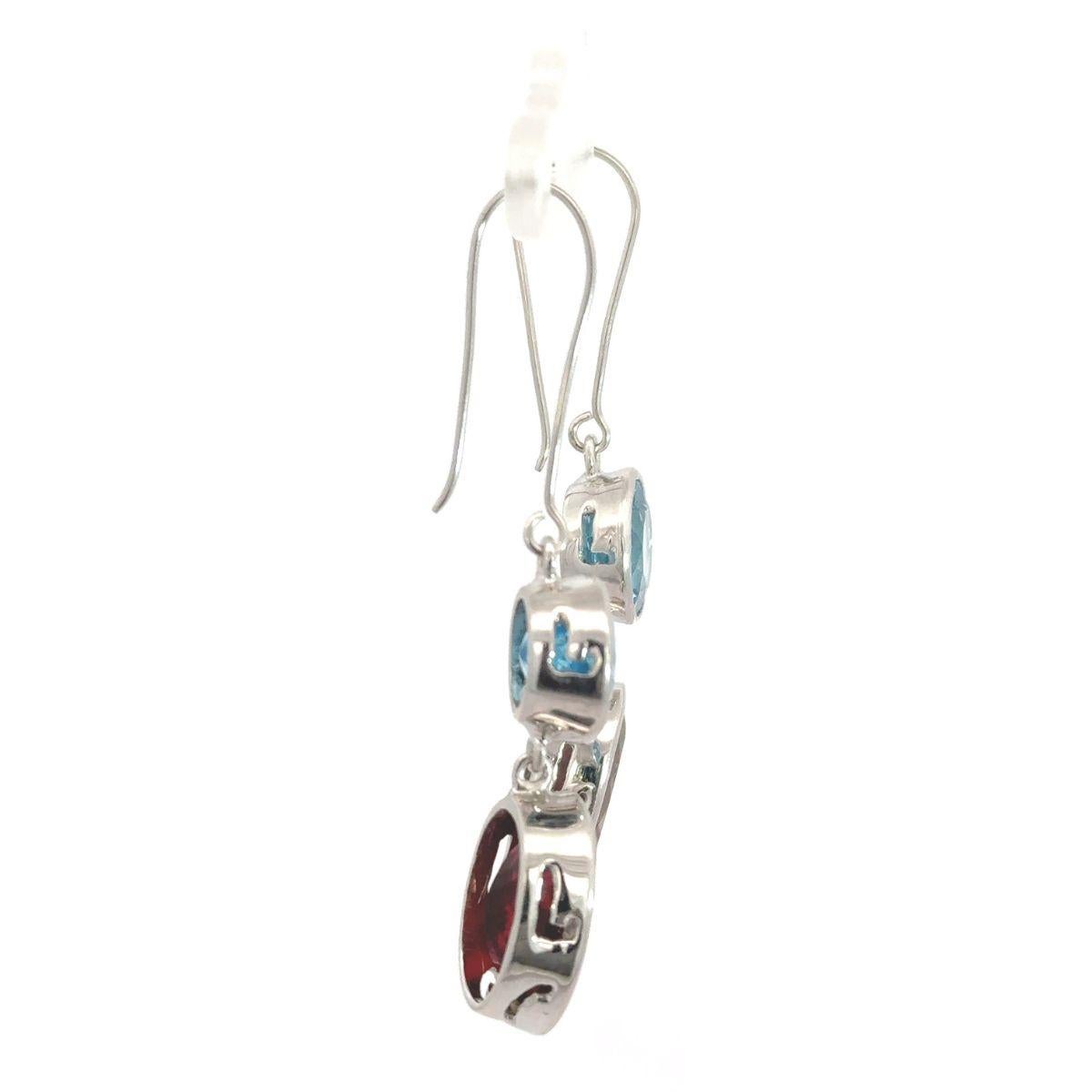 Questi orecchini a goccia in argento sterling con gemme di topazio blu e granato, realizzati a mano, sono caratterizzati da una straordinaria combinazione di colori e forme. Incastonato in argento sterling 925, ogni orecchino presenta un vibrante