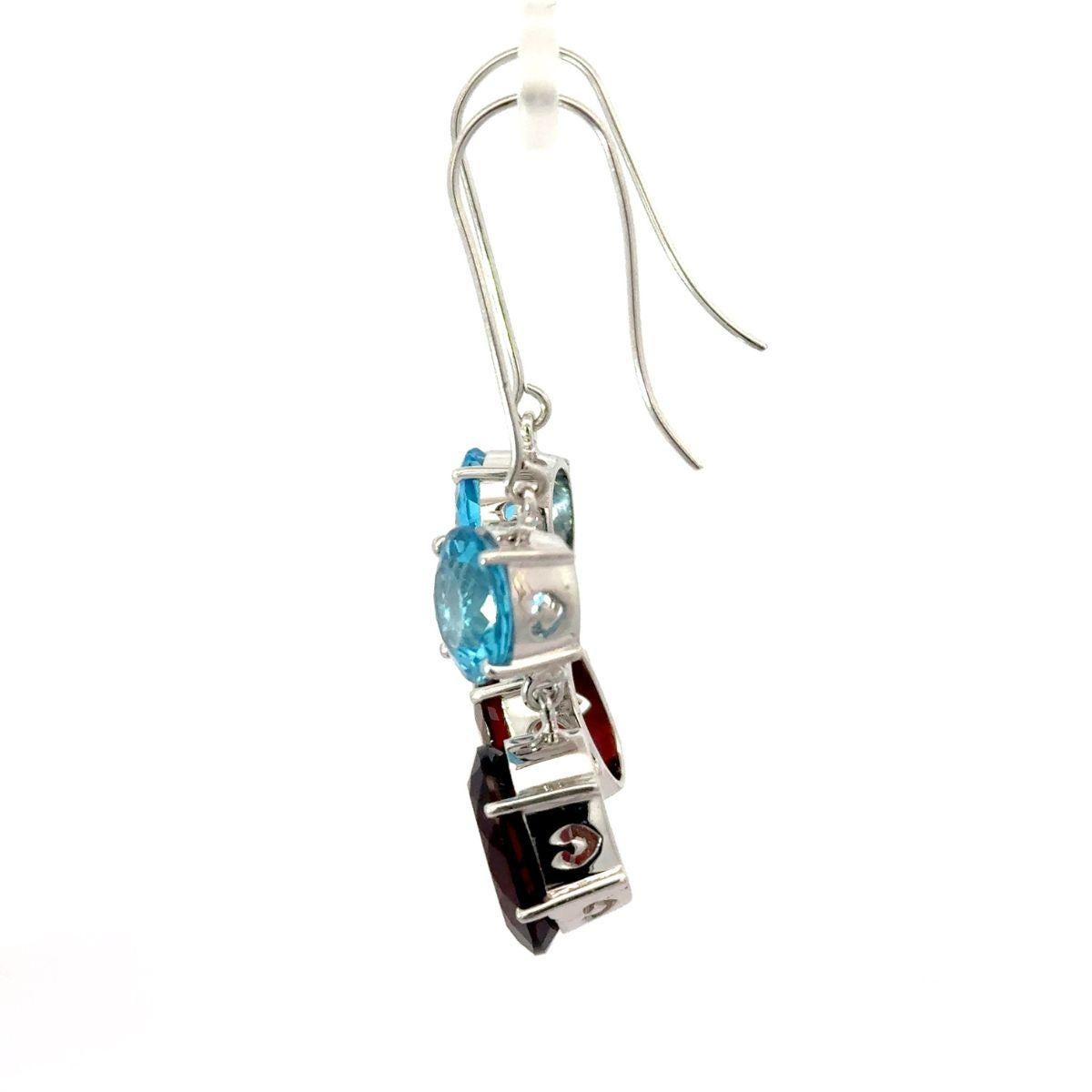 Questi orecchini pendenti in argento con granato naturale e topazio a due pietre sono realizzati a mano e presentano una vivace combinazione di gemme naturali in argento sterling 925. Un luminoso topazio blu a taglio rotondo si trova sopra un ricco