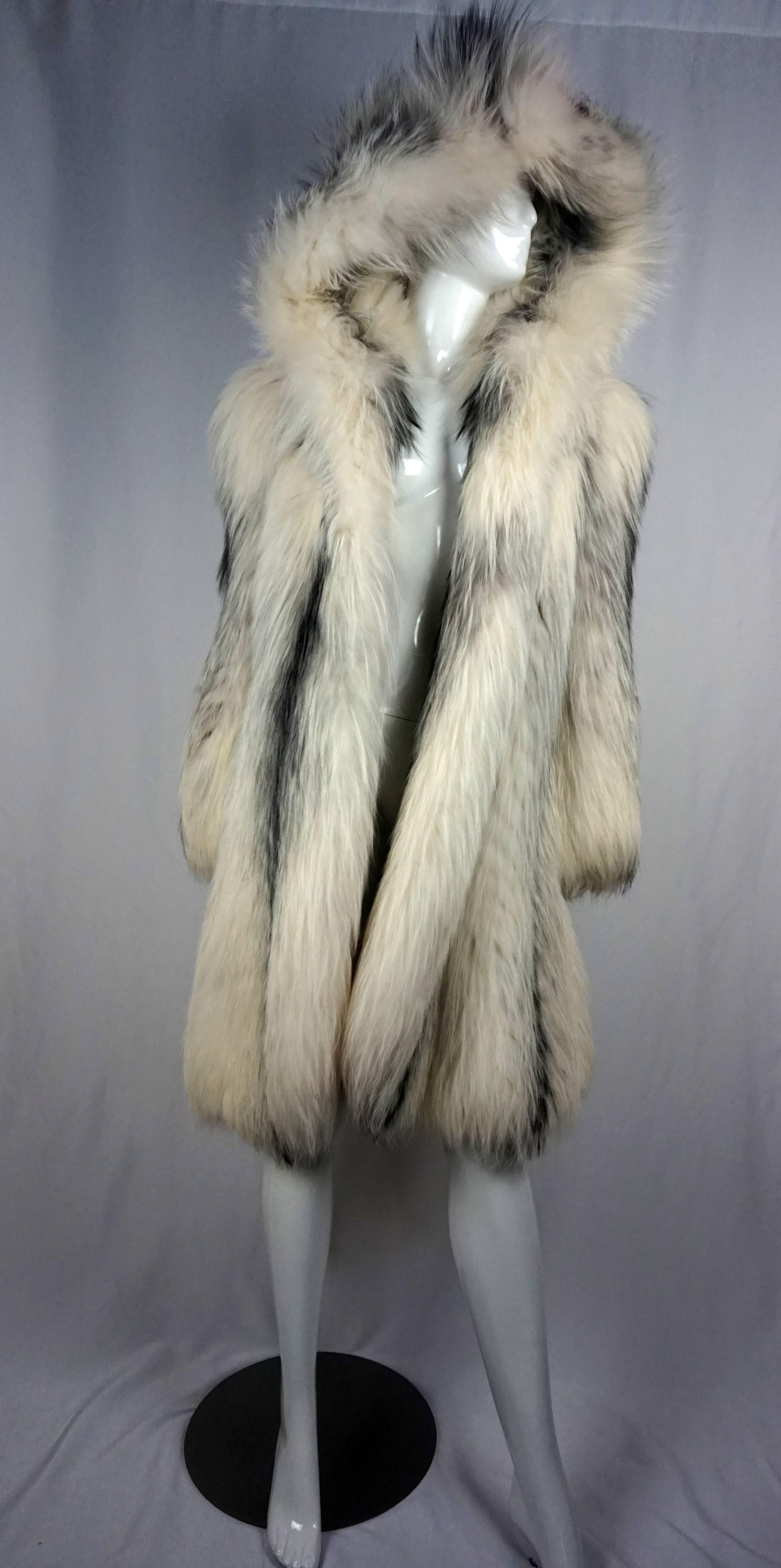 This lush and gorgeous silver fox fur is true piece that denotes luxury at its best.

This piece is oversized with a hood that adds an extra element of drama and fashion and has a simplistic leather belt which adds to a 1980s does 40s