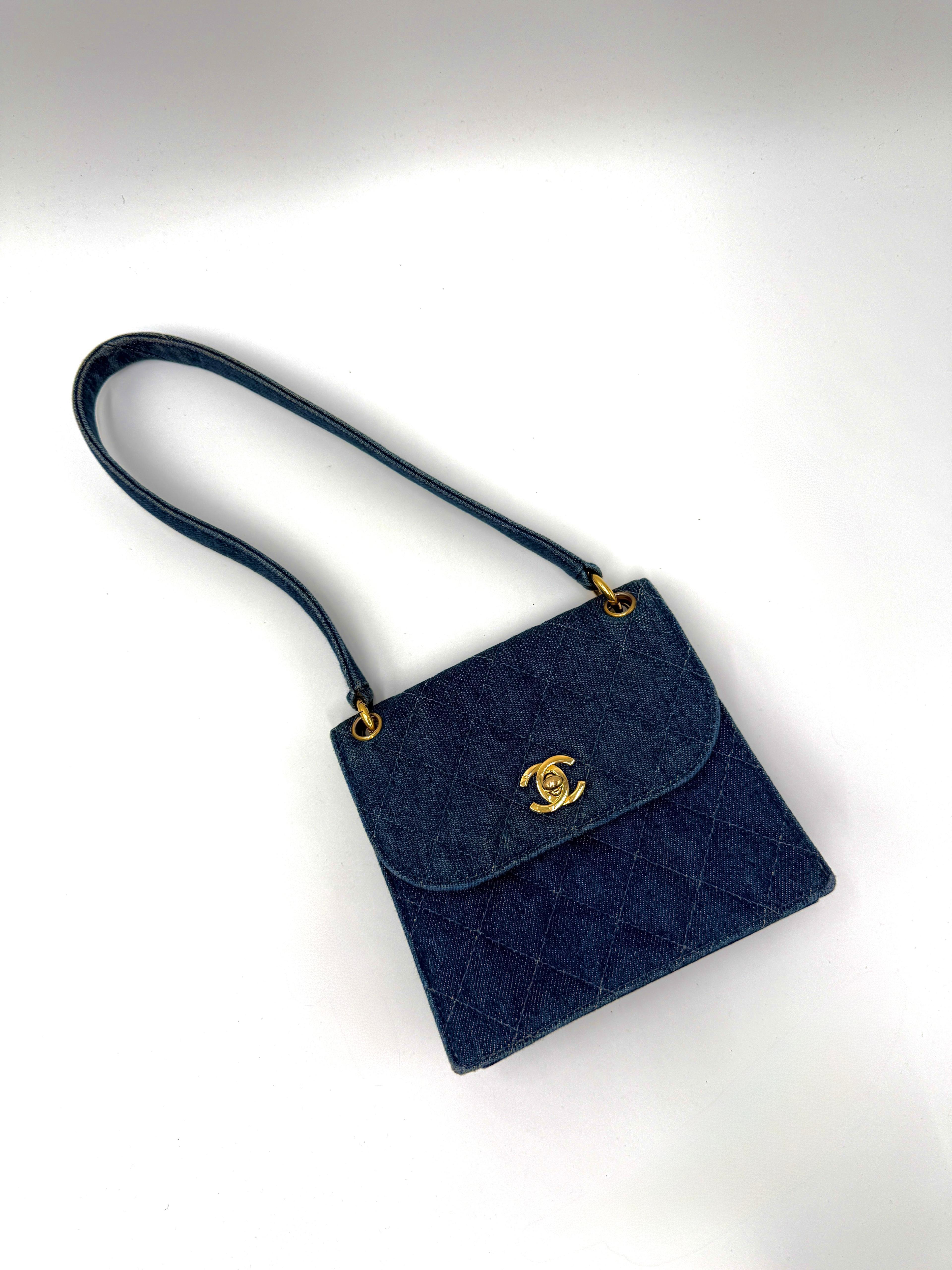 Ce mini sac Chanel vintage a été réalisé en denim bleu matelassé. Il est doté de ferrures dorées et d'une bandoulière unique. Le rabat avant est sécurisé par la fermeture classique CC à verrou tournant. Compact et polyvalent, il constitue un