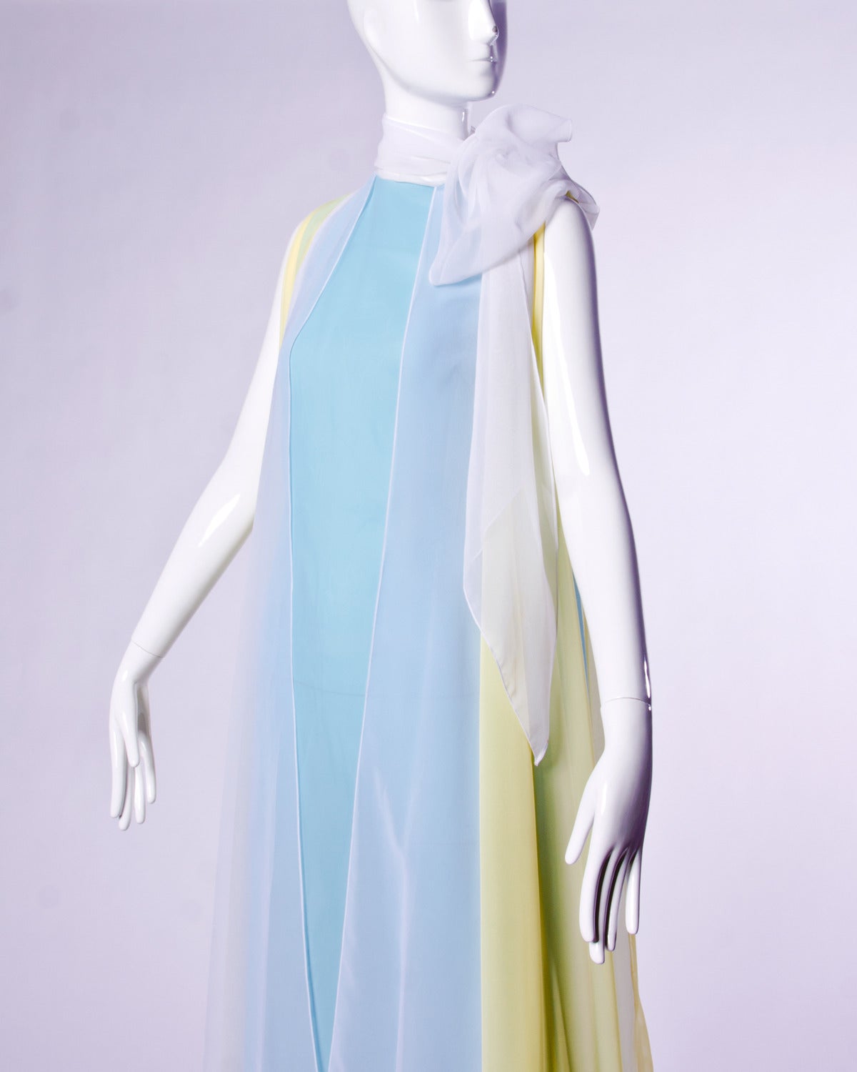 Phenomenal 1970s vintage maxi dress in pastel blue, yellow and white. This dress features a full sweep and color block design. Attached scarf can be worn tied at the neck or let hang loose.

Details:

Fully Lined
Back Zip and Hook