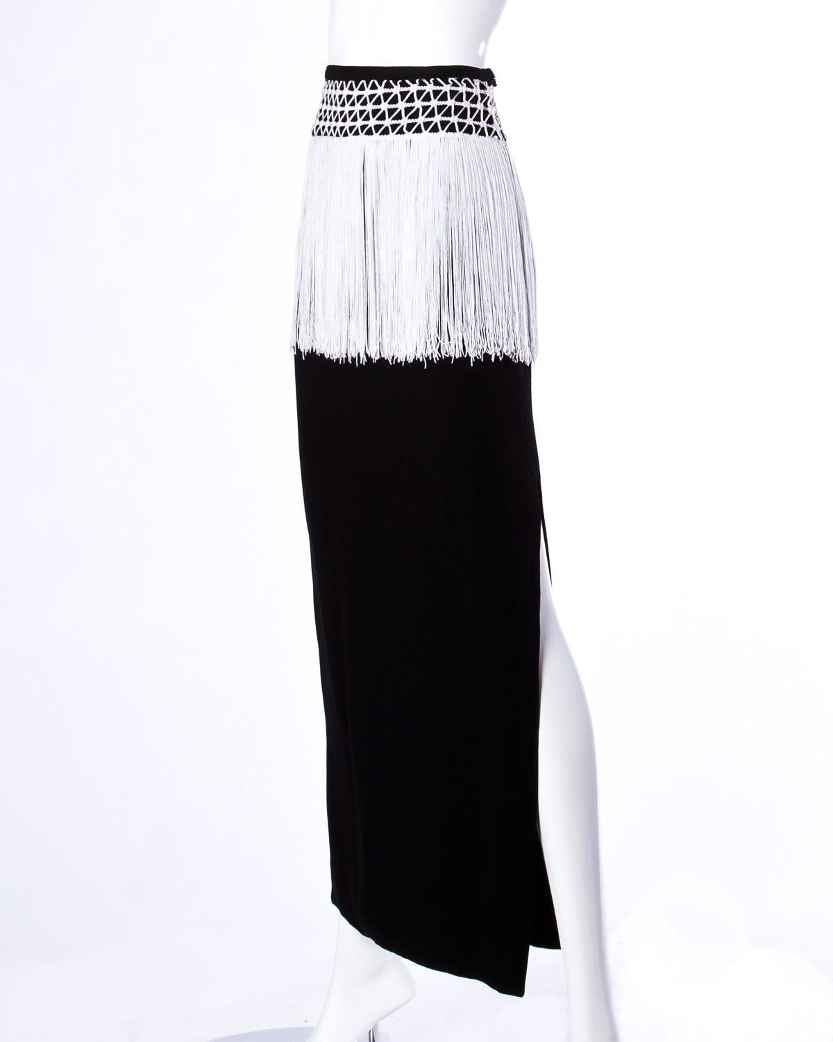 Vintage Valentino maxi skirt with a side slit and white fringe trim.

Details:

Fully Lined
Side Button Zip and Snap Closure
Marked Size: 6
Color: Black/ White
Label: Valentino Boutique/ Henri Bendel

Measurements:

Waist: 24