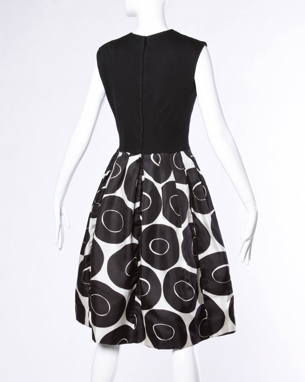 Graphic geometric print cocktail dress in black and white. Crepe bodice and full pleated skirt.

Details:

Fully Lined Bodice with Cotton Backing on the Skirt
Rear Zip and Hook Closure
Colors: Black / White
Estimated Size: