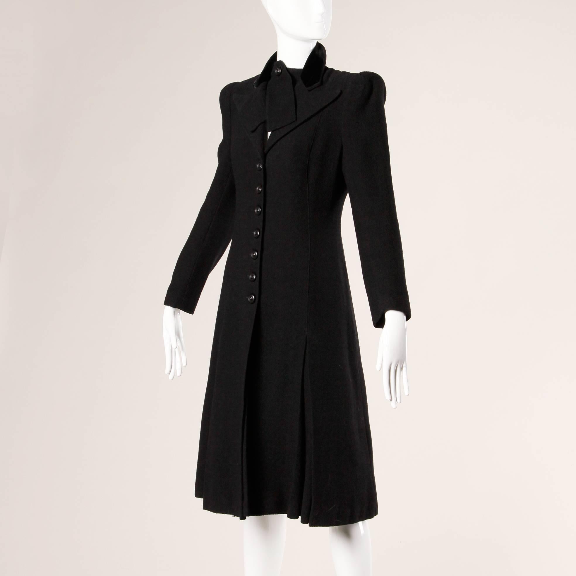 Gorgeous black wool tailored coat from the 1940s featuring bold shoulders and flared princess shape. Unique collar detail buttons under the lapels giving the appearance of a second piece.

Details:

Fully Lined
Front Button Closure
Estimated