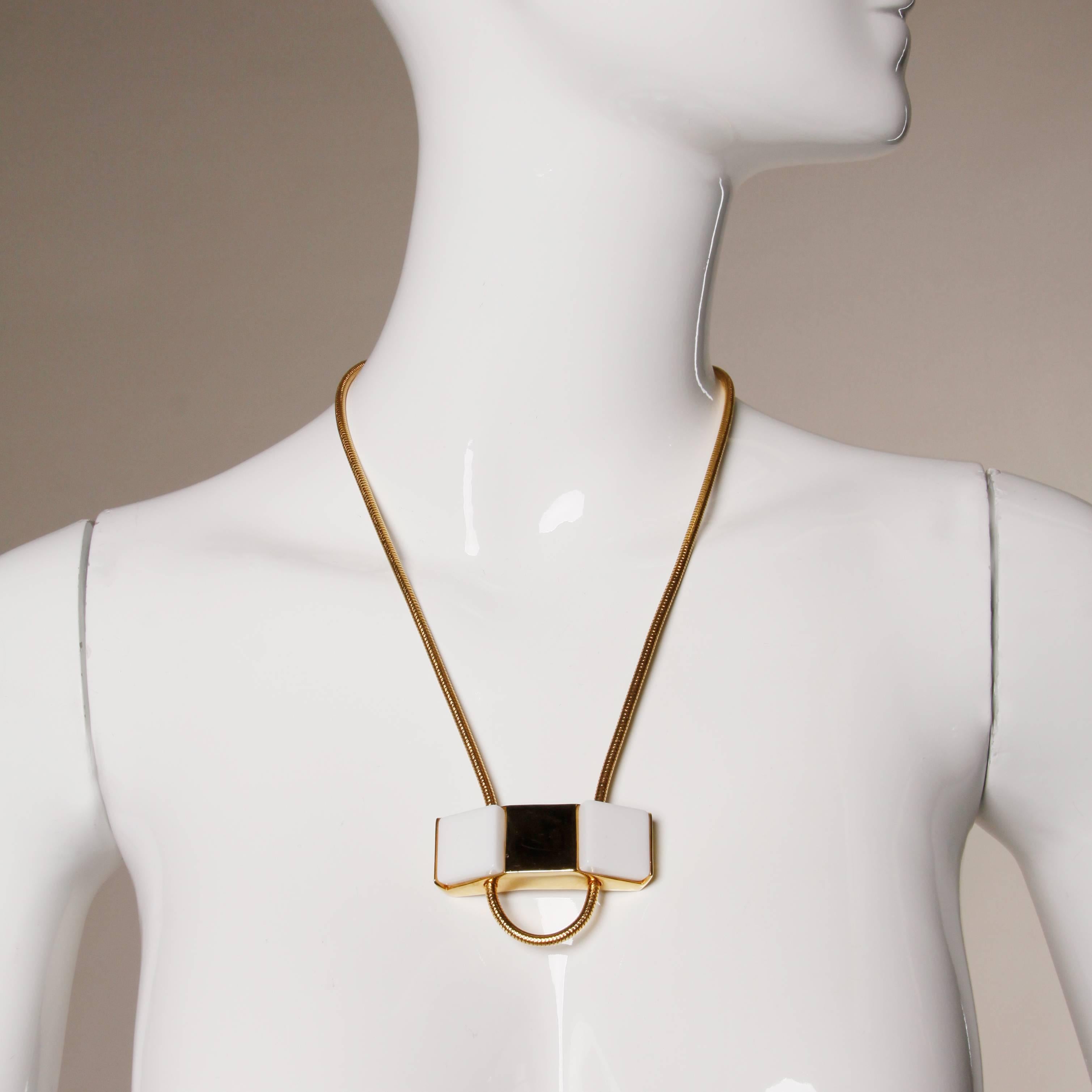 Incredible vintage 1960s Pierre Cardin gold tone modernist necklace. Chunky geometric shape with white acrylic squares and snake chain. Signed on the back of the piece. The pendant measures 2.5