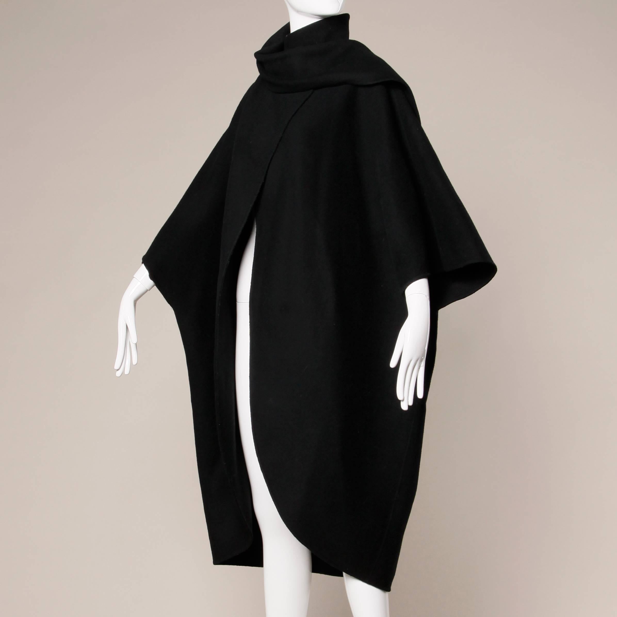 Incredible vintage black wool cape coat with attached scarf and cocoon shape by Salvatore Ferragamo. Giant bat wing sleeves and asymmetric hook closure. Unlined. Fabric content is 80% wool 20% nylon. The marked size is medium but the cape should fit