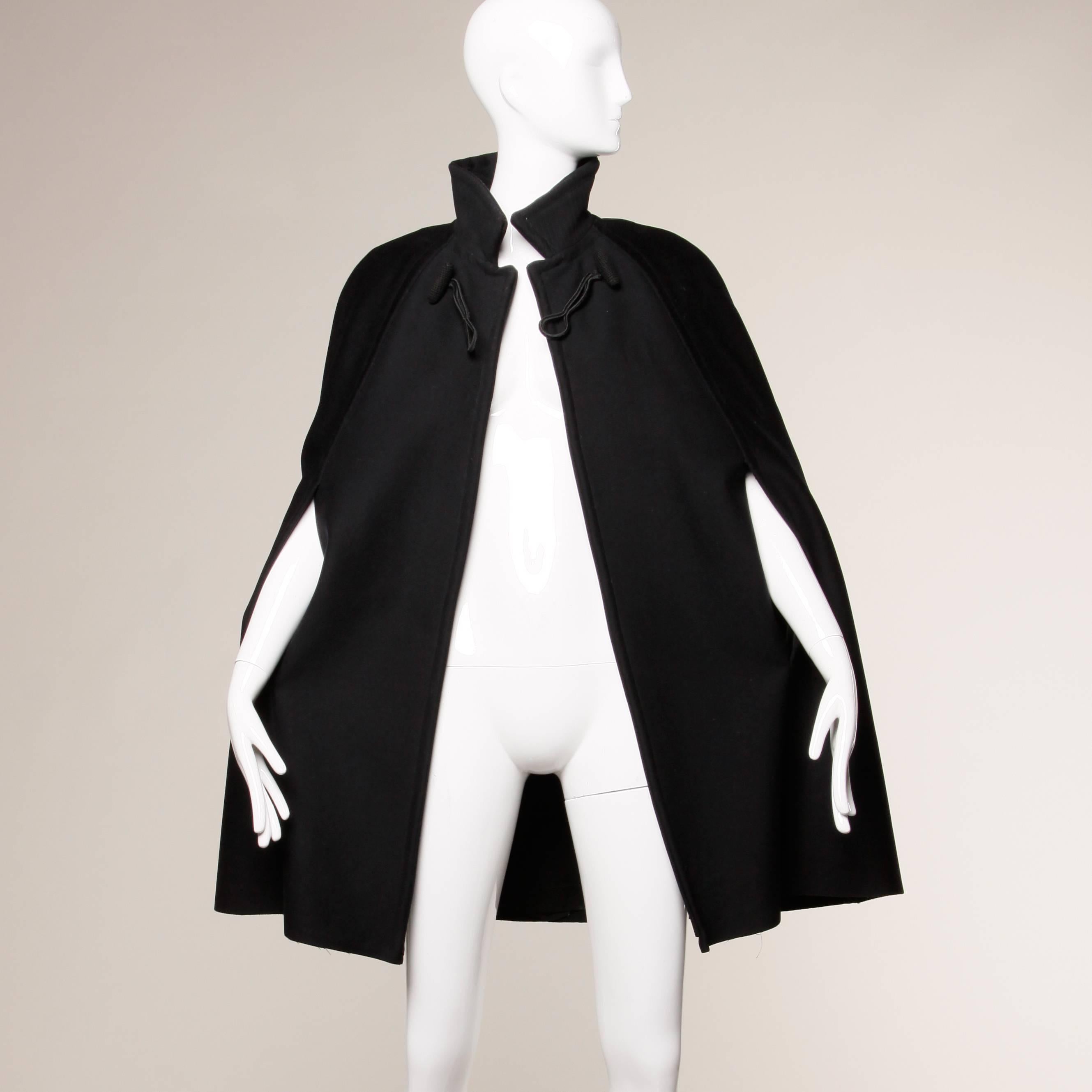 Gorgeous vintage black boiled wool cape coat with top stitching. Arm slits. Fully lined. Front closure. Total length measures 36