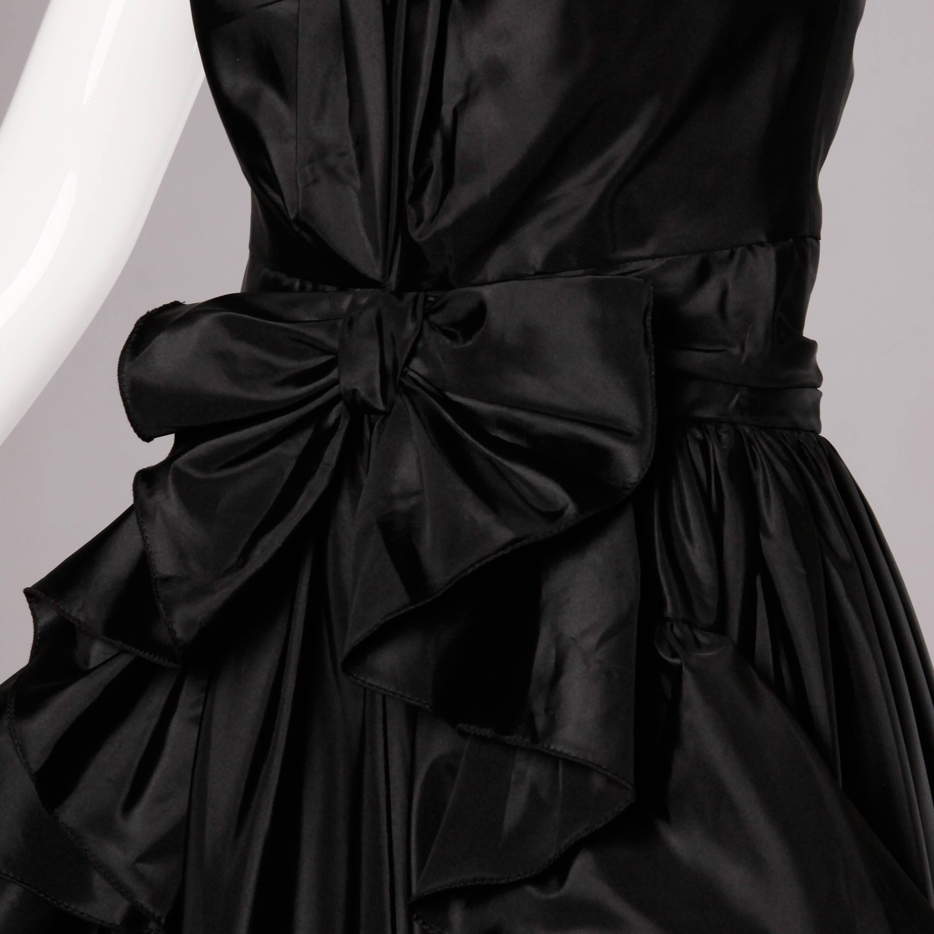 Début des années 1980 inspiré par les années 1950 ! Cette robe de soirée Jean Varon présente des volants et un nœud sur le devant. Partiellement doublé avec fermeture éclair à l'arrière. Fabriqué en Angleterre. La taille indiquée est un UK 12, mais