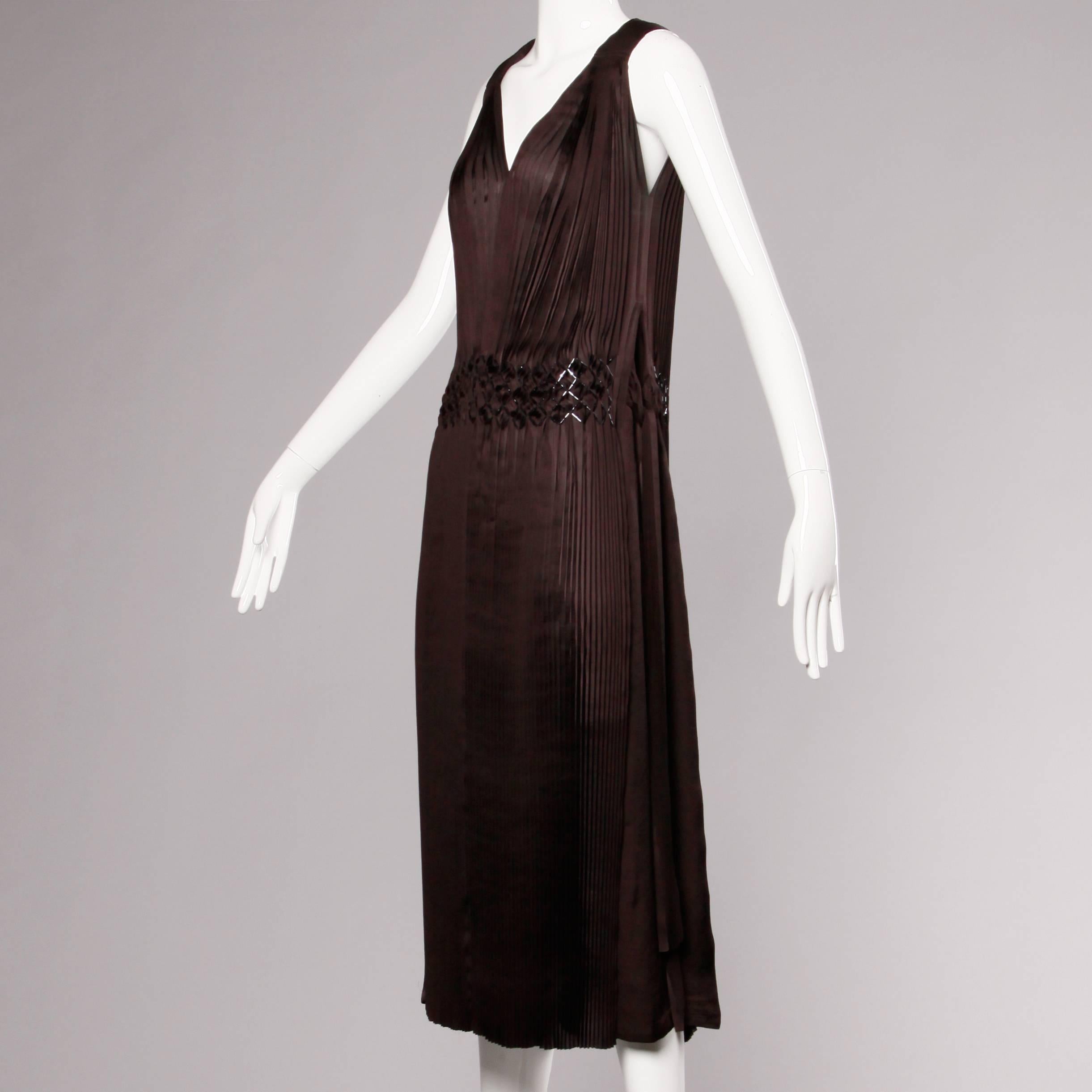 Incredible dark brown 1920s-inspired flapper dress by Issey Miyake with side ties and intricate beadwork along the low waist. Deep plunging neckline and flattering body hugging shape. Unlined. Side ties are adjustable. Marked size is a Japan 04.