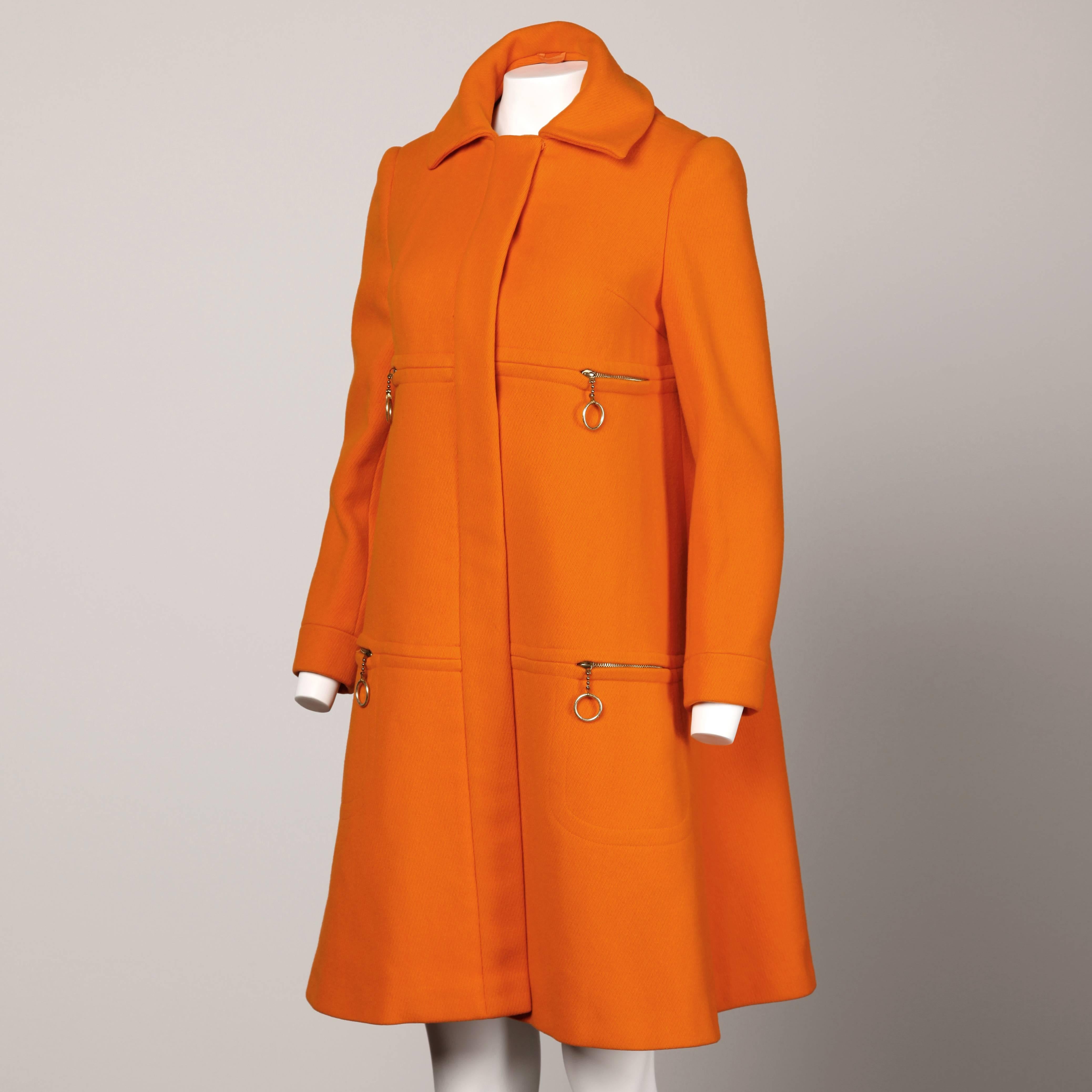 Iconic vintage 1960s bright orange wool trapeze coat by Mary Quant's The Ginger Group. Huge sweep and zippered pockets with ultra mod ring pulls. Beautiful top stitching and 1960s silhouette. Fully lined. 100% wool. Hidden front button closure. Will