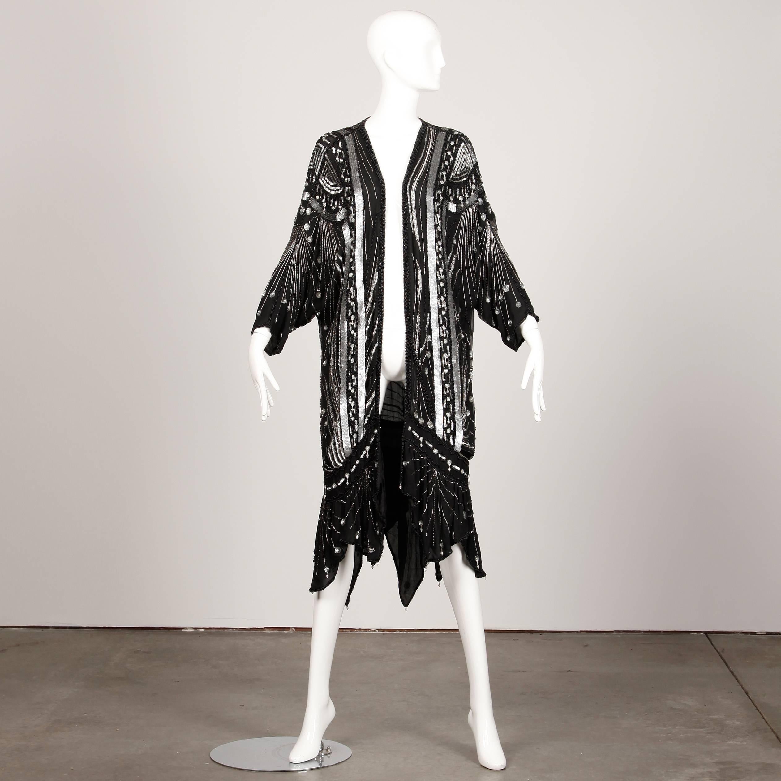 Sparkling Art Deco-inspired silk duster completely encrusted with thousands of sparkling sequins and beads. Scarf hem hits mid-calf. Fully lined in silk with front hook closure. This piece should fit most sizes on account of the oversized shape. The