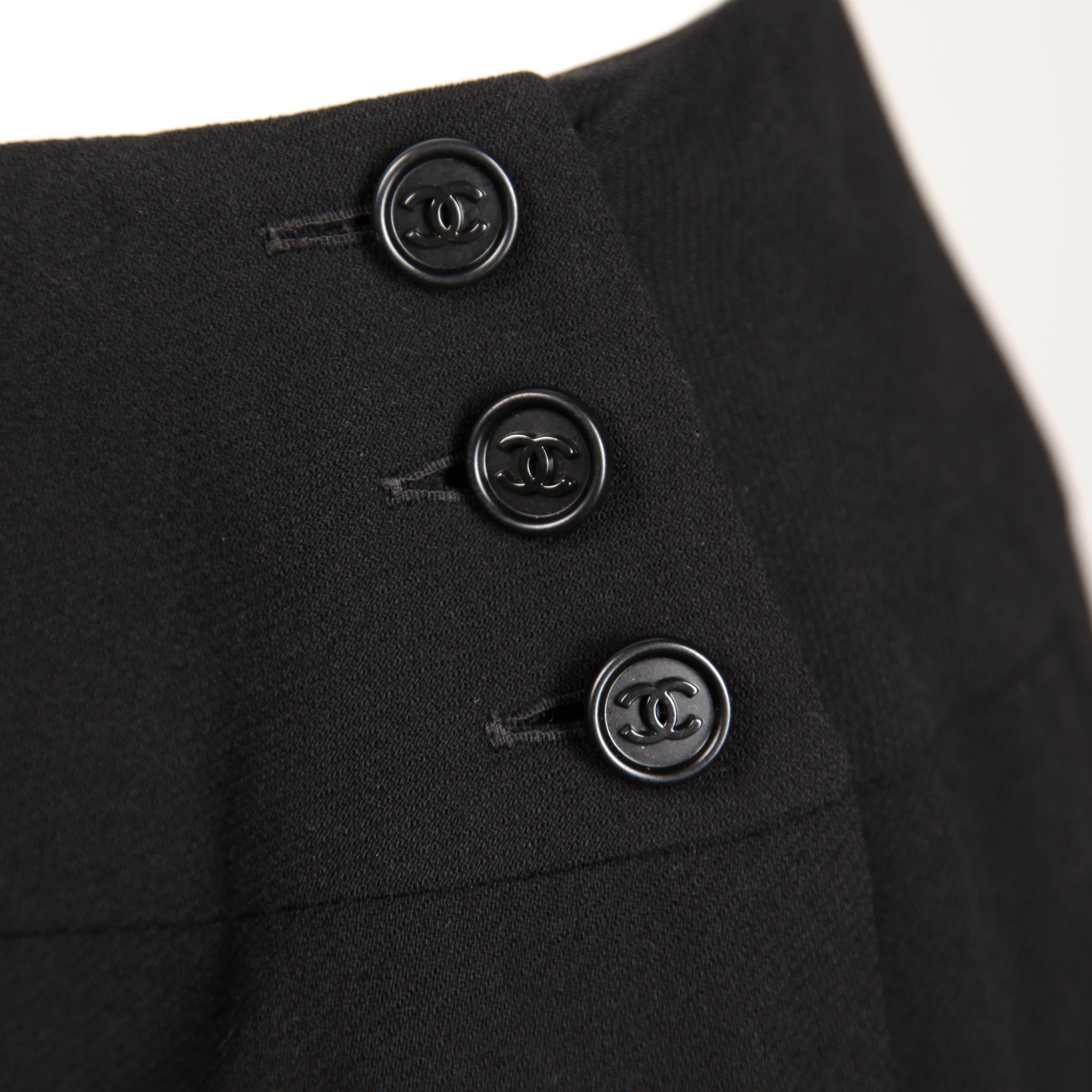 Classic Chanel black wool pleated skirt in a harder-to-find larger size 44. Fully lined in silk, the skirt buttons up on one side with three "CC" buttons. Beautiful construction! This fits like a modern size large. The low waist measures