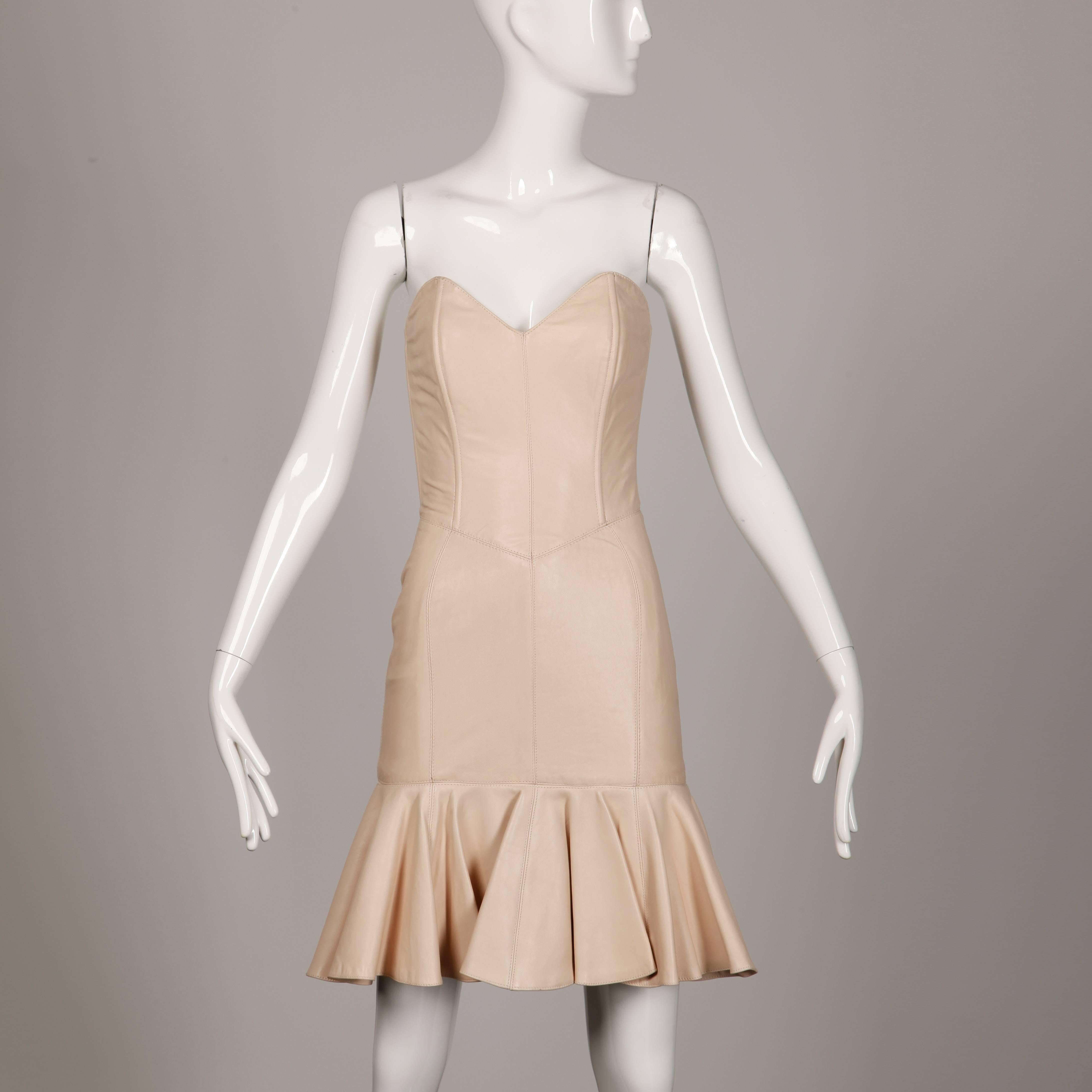 Soft blush pink leather dress by Michael Hoban for North Beach Leather. Strapless sweetheart bust and ruffled hem. Sexy body hugging fit. This piece is fully lined and features rear zip and hook closure. The marked size is XS and the dress fits true
