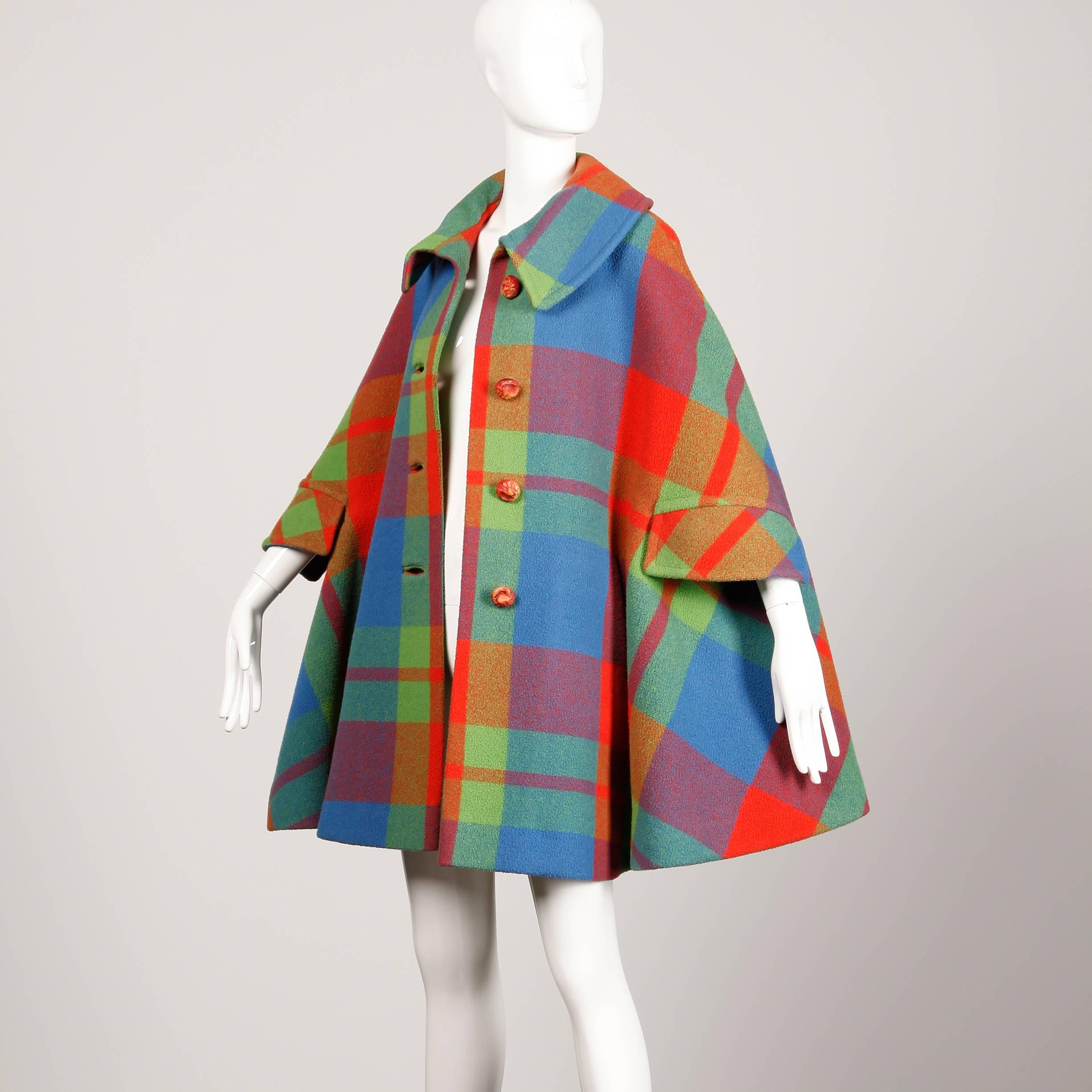 Vibrant vintage plaid wool cape coat from the 1960s by George Richards. Arm slits and side pockets. Front button closure with satin lining. This piece is in excellent vintage condition with no noted flaws. It should fit most sizes XS-XL.