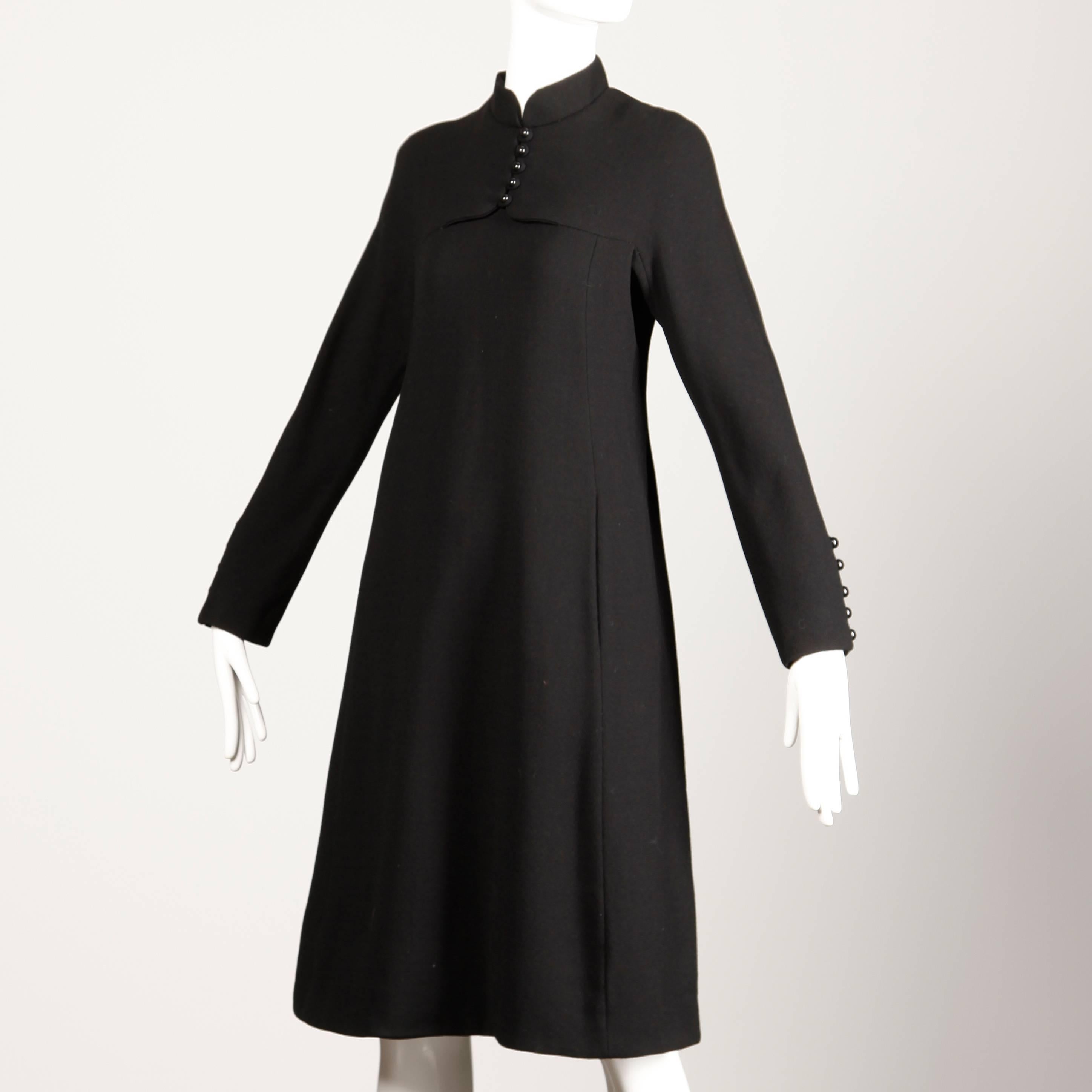 Vintage 1960s black wool Geoffrey Beene shift dress with long sleeves and button detail. 

Details: 

Fully Lined In Silk Organza
Front Pockets in Seam
Back Metal Zip Closure
Estimated Size: Medium
Color: Black
Fabric: Wool 
Label: Geoffrey