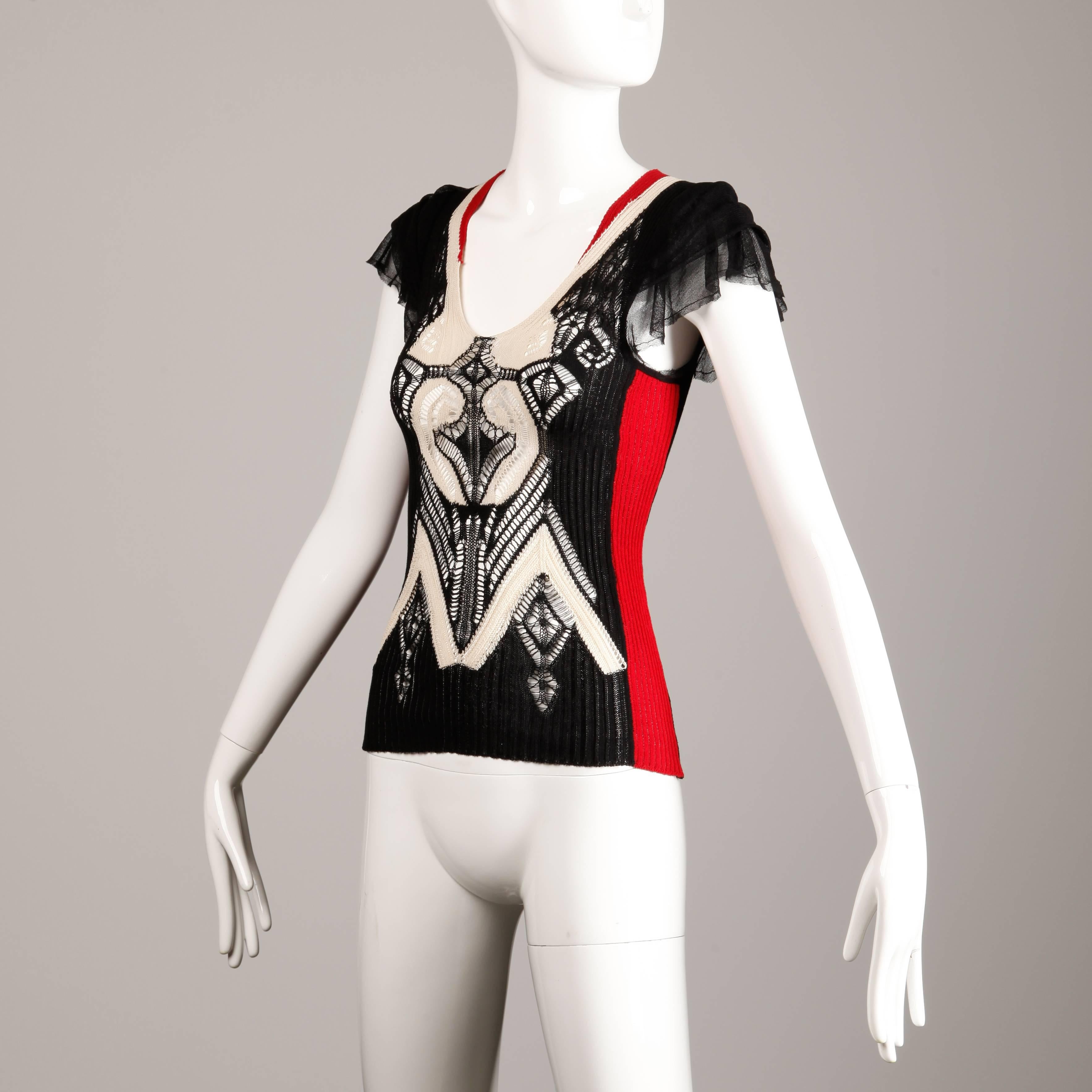 Fantastic Jean Paul Gaultier knit top with black mesh flutter sleeves in red, black and cream. The fabric content is 80% cotton, 15% silk, and 5% elastane. Marked size small and the top fits true to size. The bust measures 28-34", waist