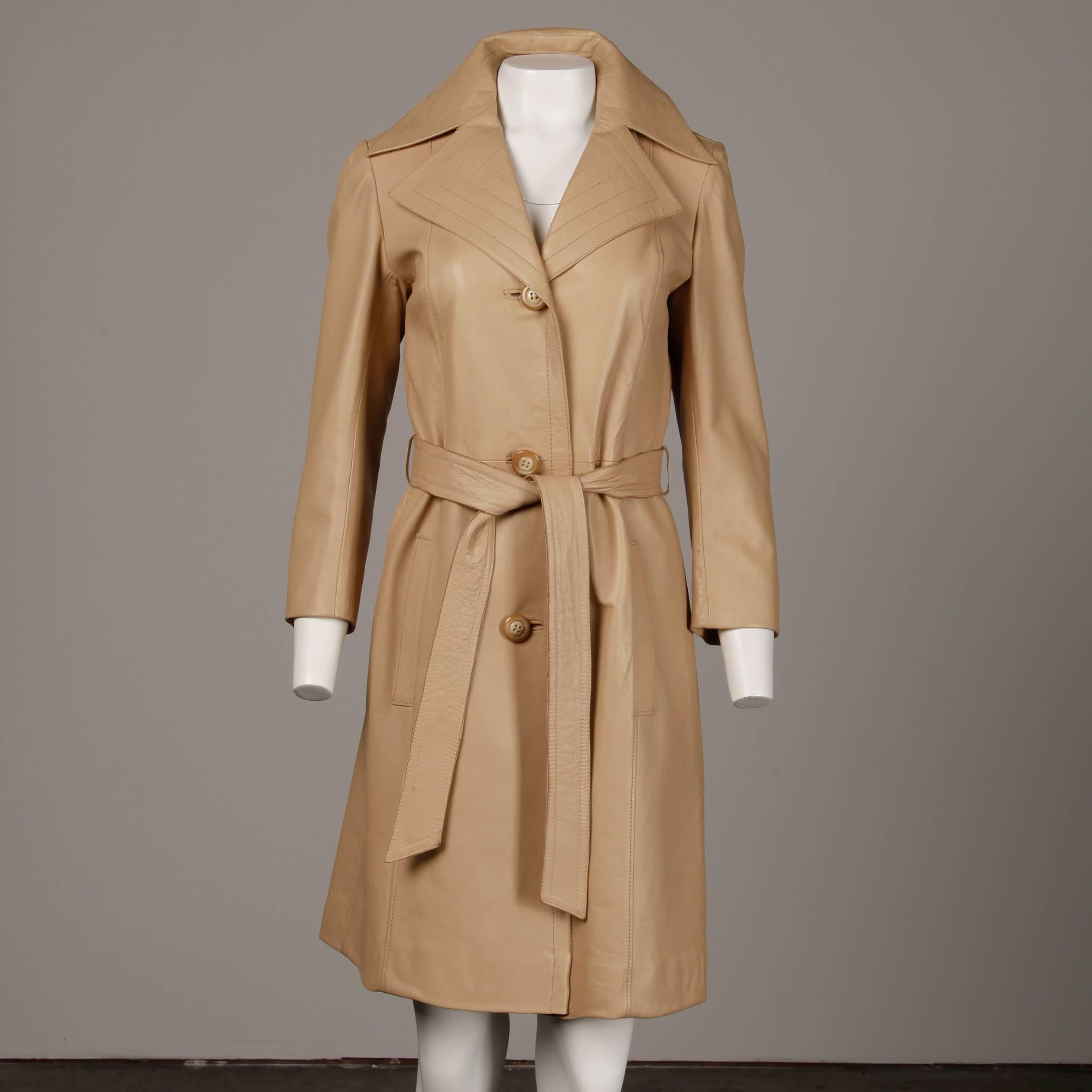 Gorgeous soft beige leather trench coat with matching tie sash belt. Fully lined with front button and tie closure. Front hidden pockets. 100% leather with !00% rayon lining. The marked size is 8, but the jacket fits like a modern size small. The