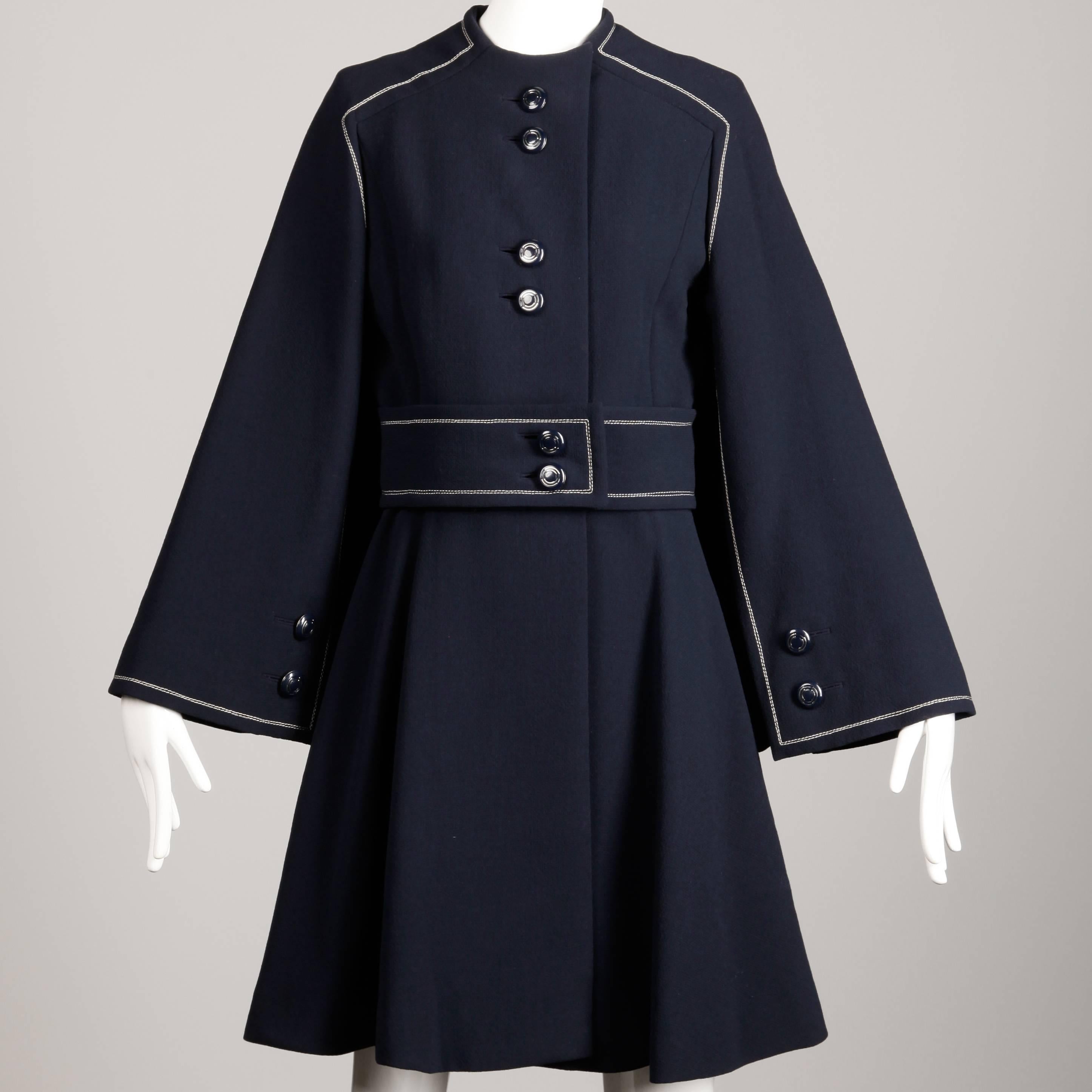 This is one of the most beautiful vintage pieces I have ever laid eyes on. The quality is absolutely exceptional and the condition is pristine. Ronald Amey designed this cape that converts to a coat when you button the sleeves. It is done in navy