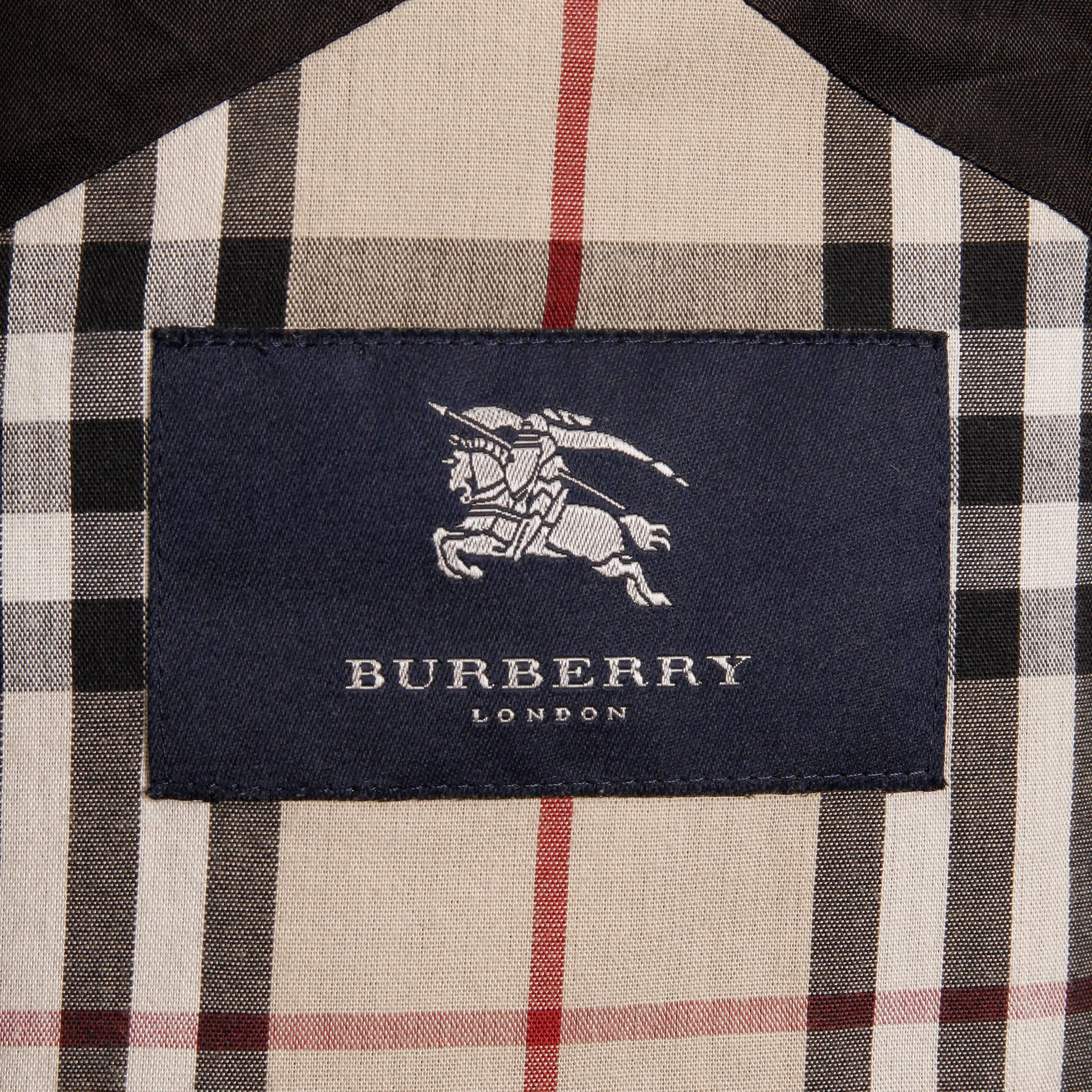 Classic Burberry raincoat with nova plaid trim and a detachable hood. Fully lined with front zip and snap closure. Hidden pockets. Removable hood with drawstring. Exterior is 100% polyester with rubber backing, lining 50% cotton, 50% polyester.