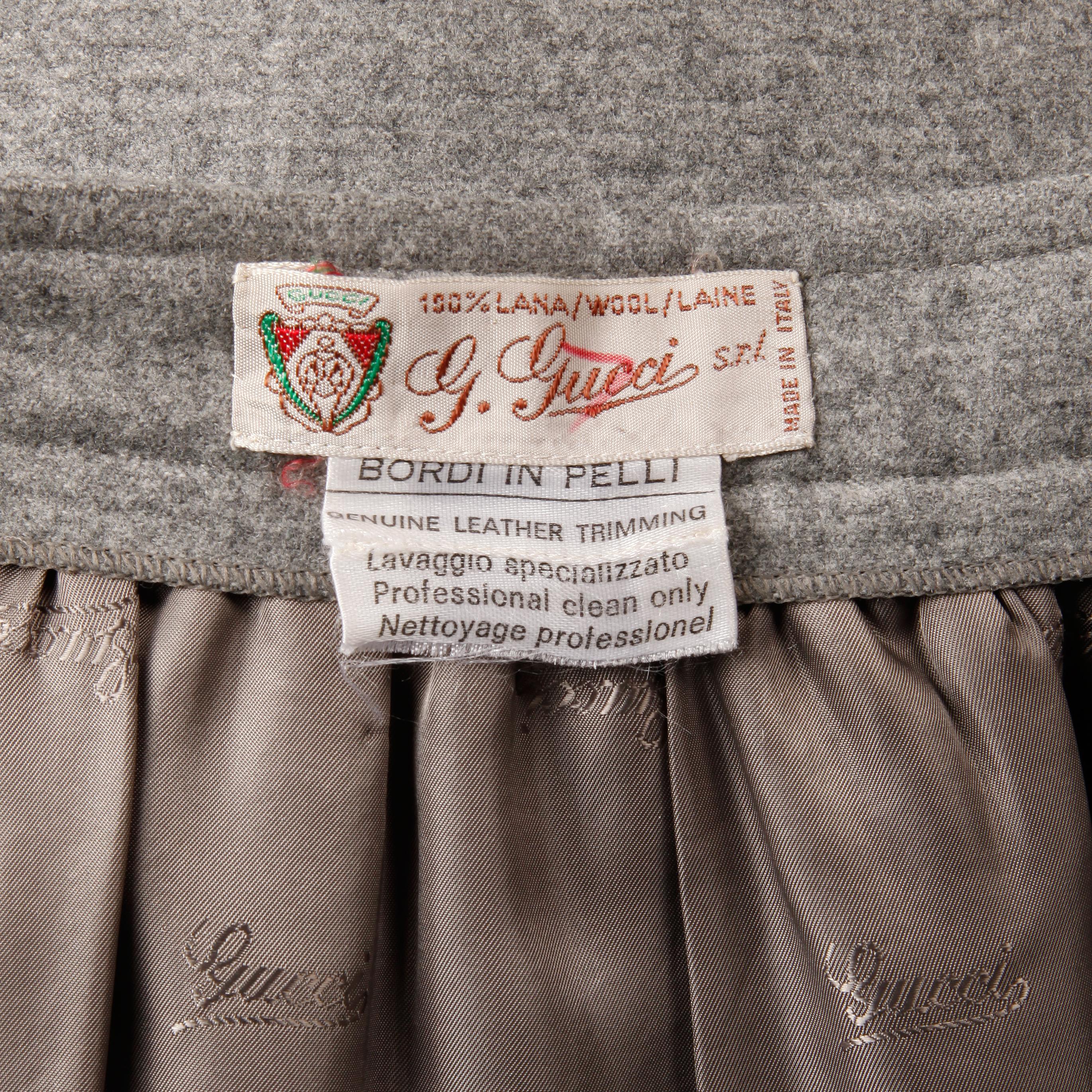 Gorgeous vintage gray wool Gucci skirt with a leather horsebit applique design from the 1970s. Fully lined with front hook closure at wrap around waist. Hidden side pockets. 100% wool. 100% genuine leather trim. Fits like a modern size small. The