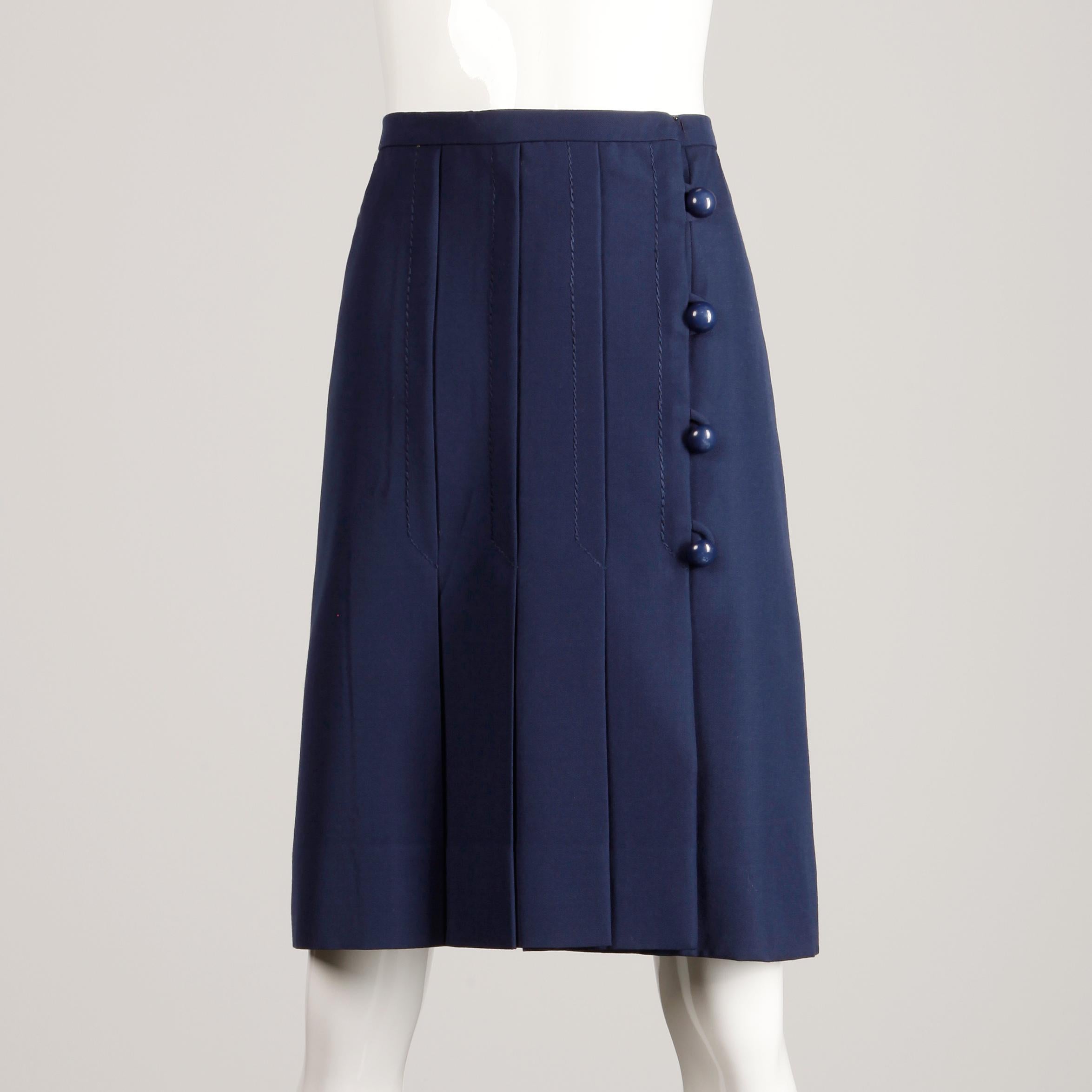 Gorgeous vintage navy blue wool skirt with pleating and asymmetric ball buttons by Jean Patou. Fully lined in silk with front wrap button and hook closure. The marked size is 8, but the skirt fits more like a modern XS-S. The waist measures 23