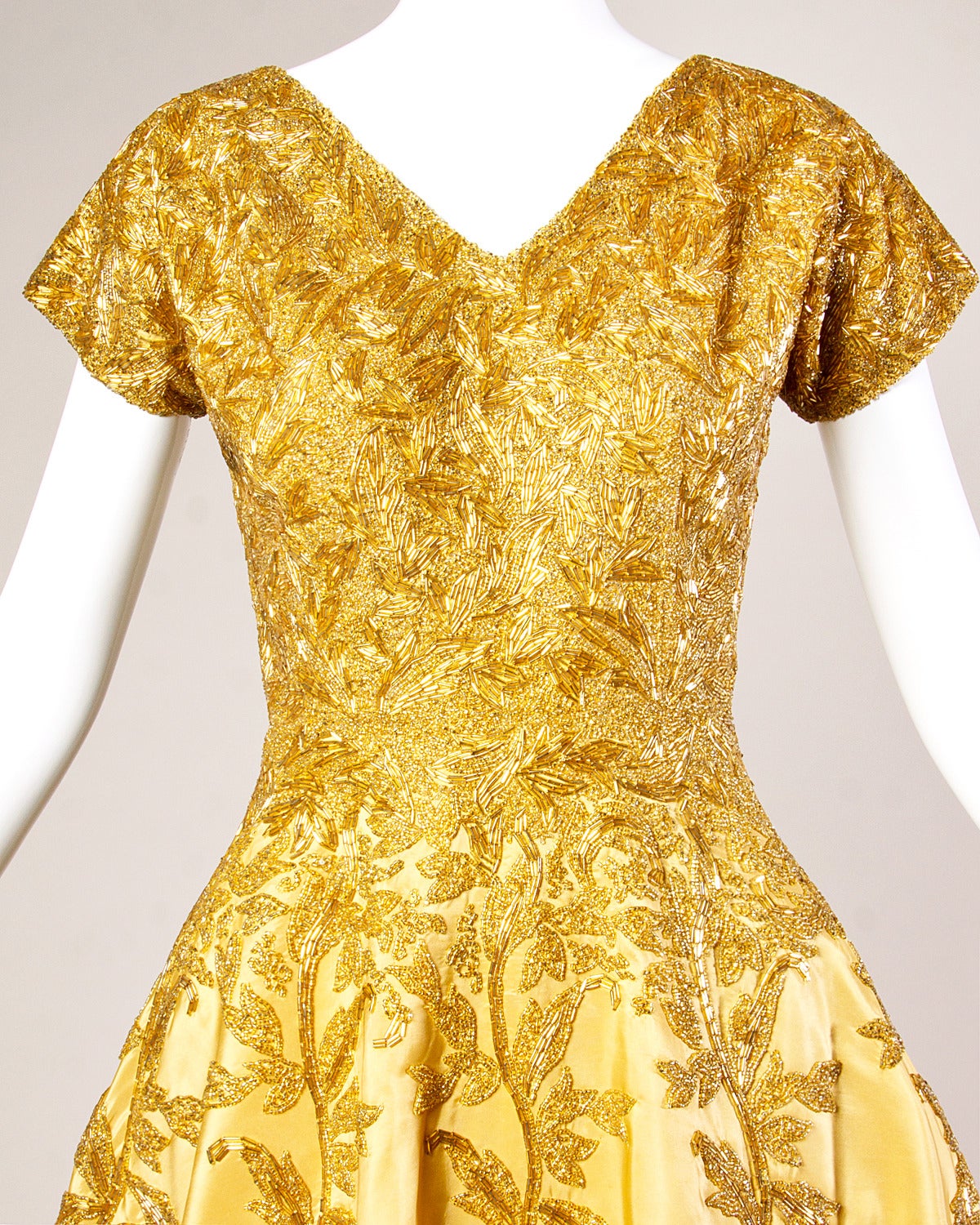 Absolutely one of the most stunning dresses we have ever laid eyes on! This dress is just incredible. Gorgeous gold-yellow silk cocktail dress with heavy hand beaded design. Full sweep, short sleeves and V-neck. 

Details:

Fully Lined
Rear