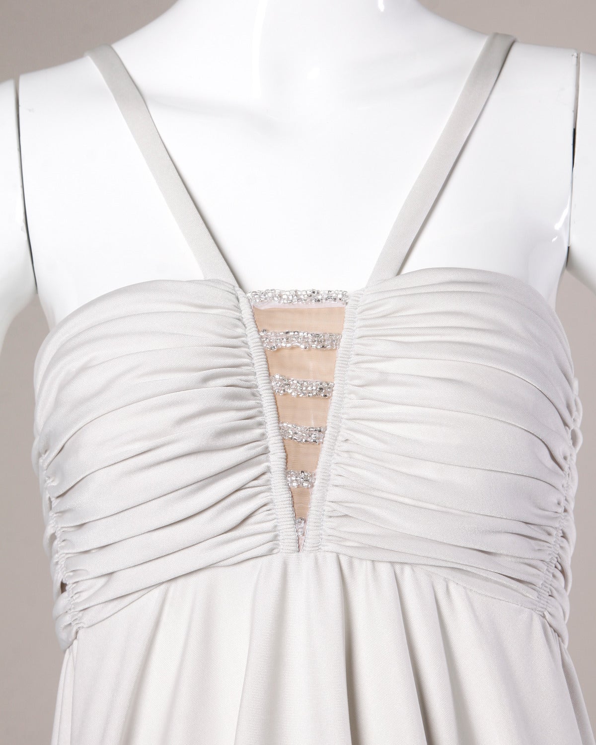 Pale gray maxi dress in slinky light weight nylon jersey. Empire waist and beaded nude illusion cut out detail at the bust. 

Details:

Partially Lined
Back Zip and Hook Closure
Estimated Size: Small
Color: Pale Gray
Fabric: Jersey
Label: