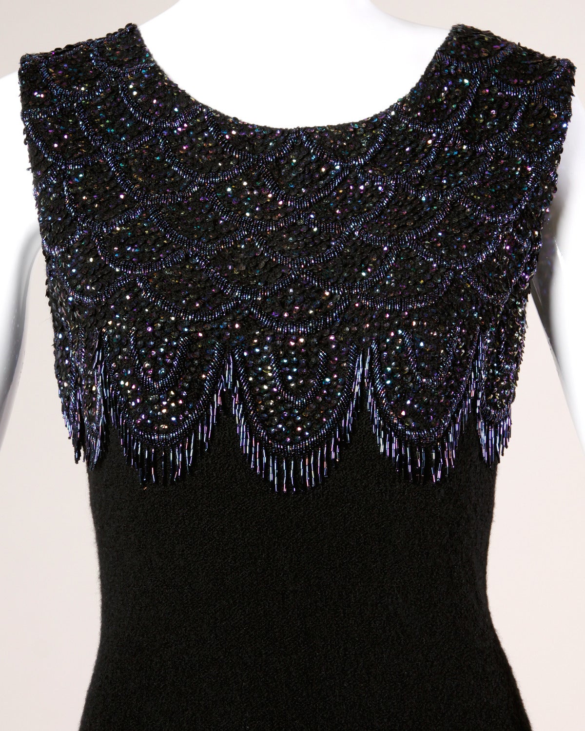 Gorgeous 1960s black soft wool knit cocktail dress with iridescent blue beadwork in a scalloped design. 

Details:

Unlined
Back Metal Zip and Hook Closure
Marked Size: 18
Estimated Size: Large
Color: Black/ Iridescent Purple/ Yellow/