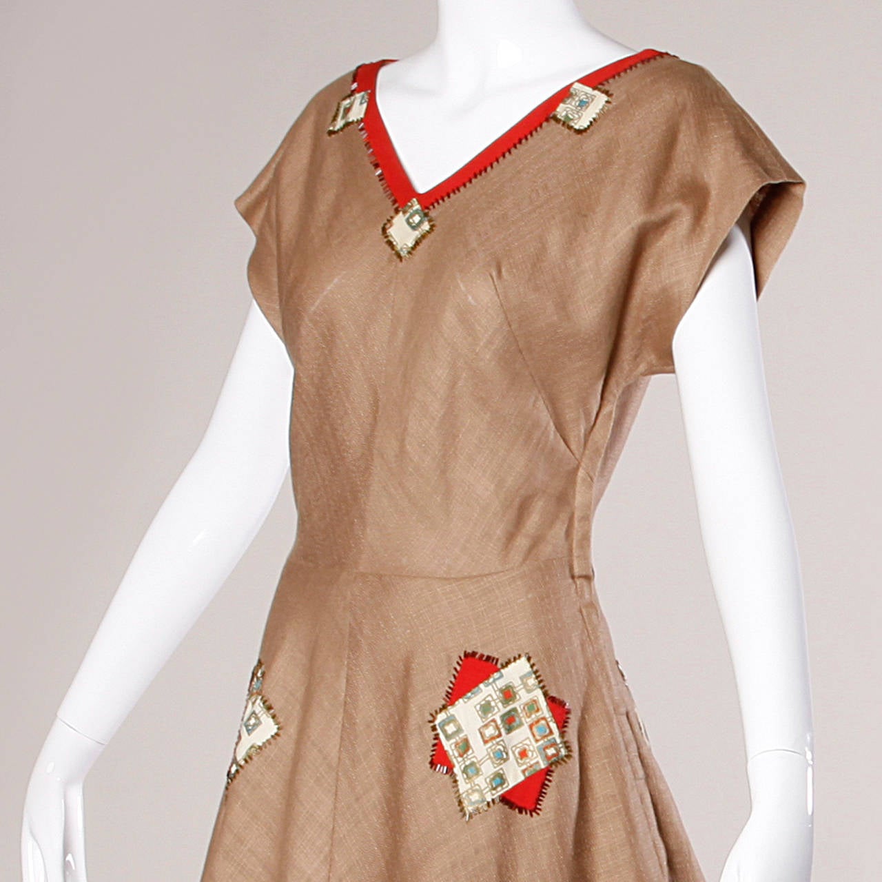 Gorgeous vintage 1950s linen dress with a darling beaded patchwork design. V-neck and full sweep.

Details:

Unlined
Side Metal Zip Closure
Marked Size: Not Marked
Estimated Size: Small-Medium
Color: Potato Sack Brown/ Red/ Green/ Blue/ Gold